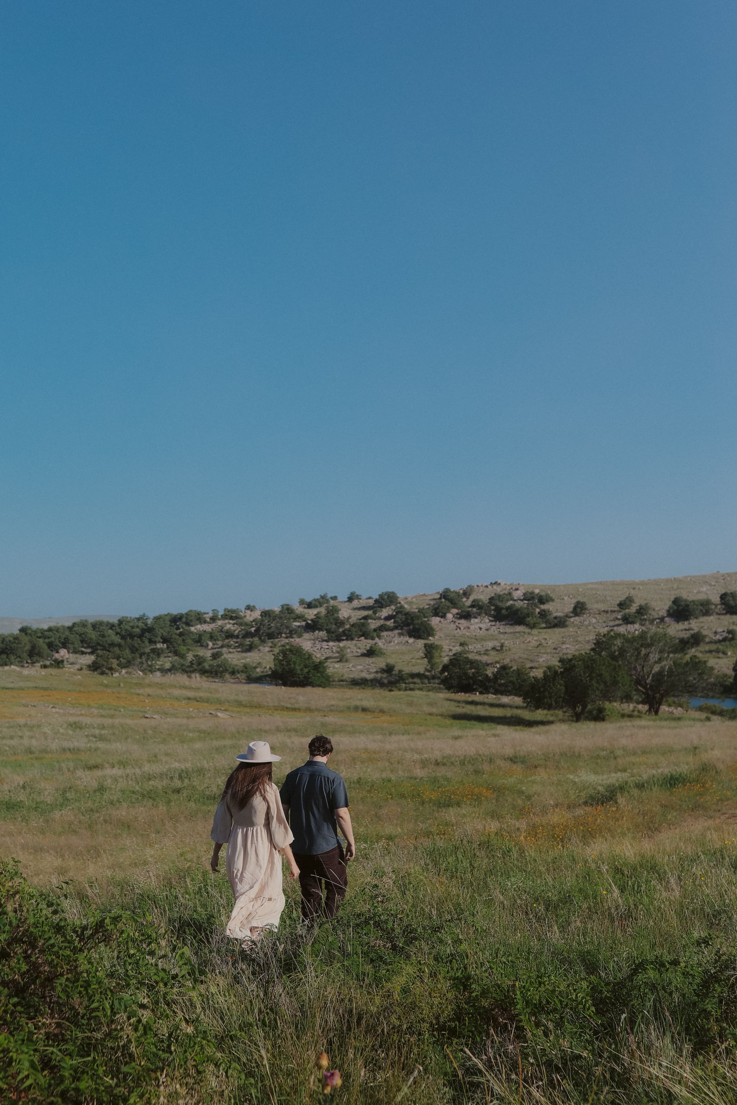 Walking together through tall prairie grass toward distant granite hills