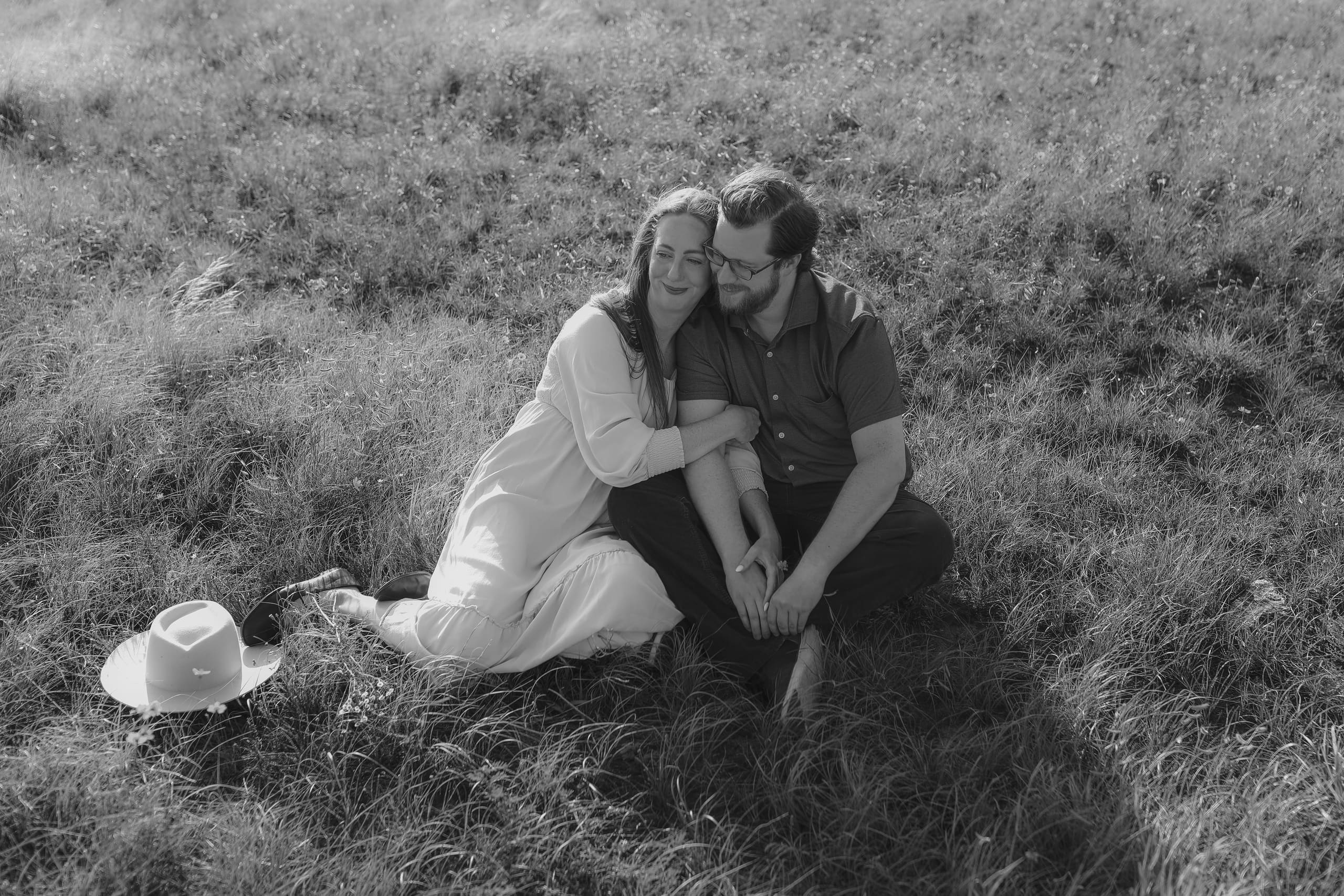 Sitting together in the tall grass, her head tucked against his cheek
