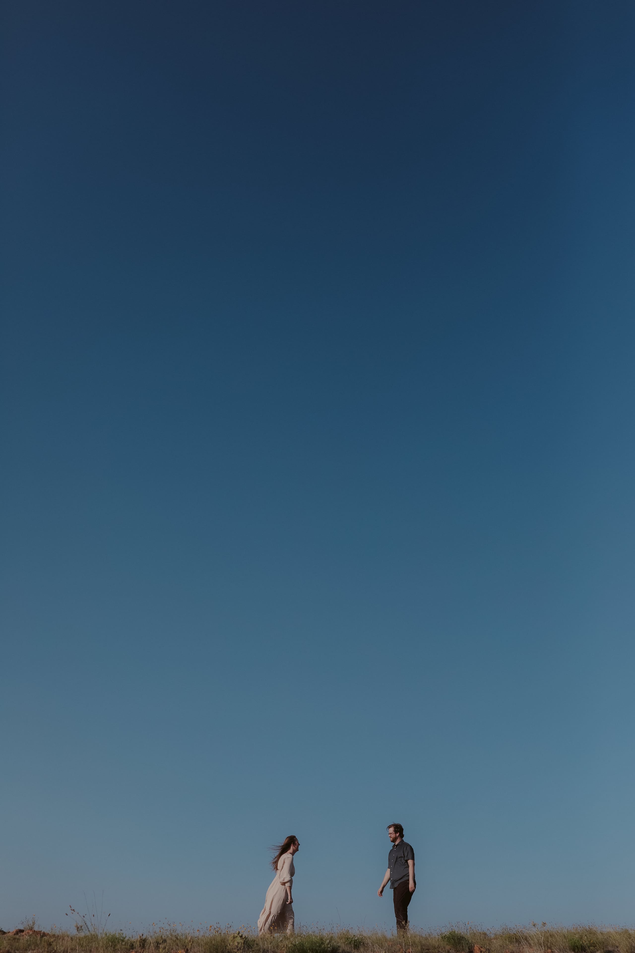 Facing each other on the ridge beneath a towering blue sky