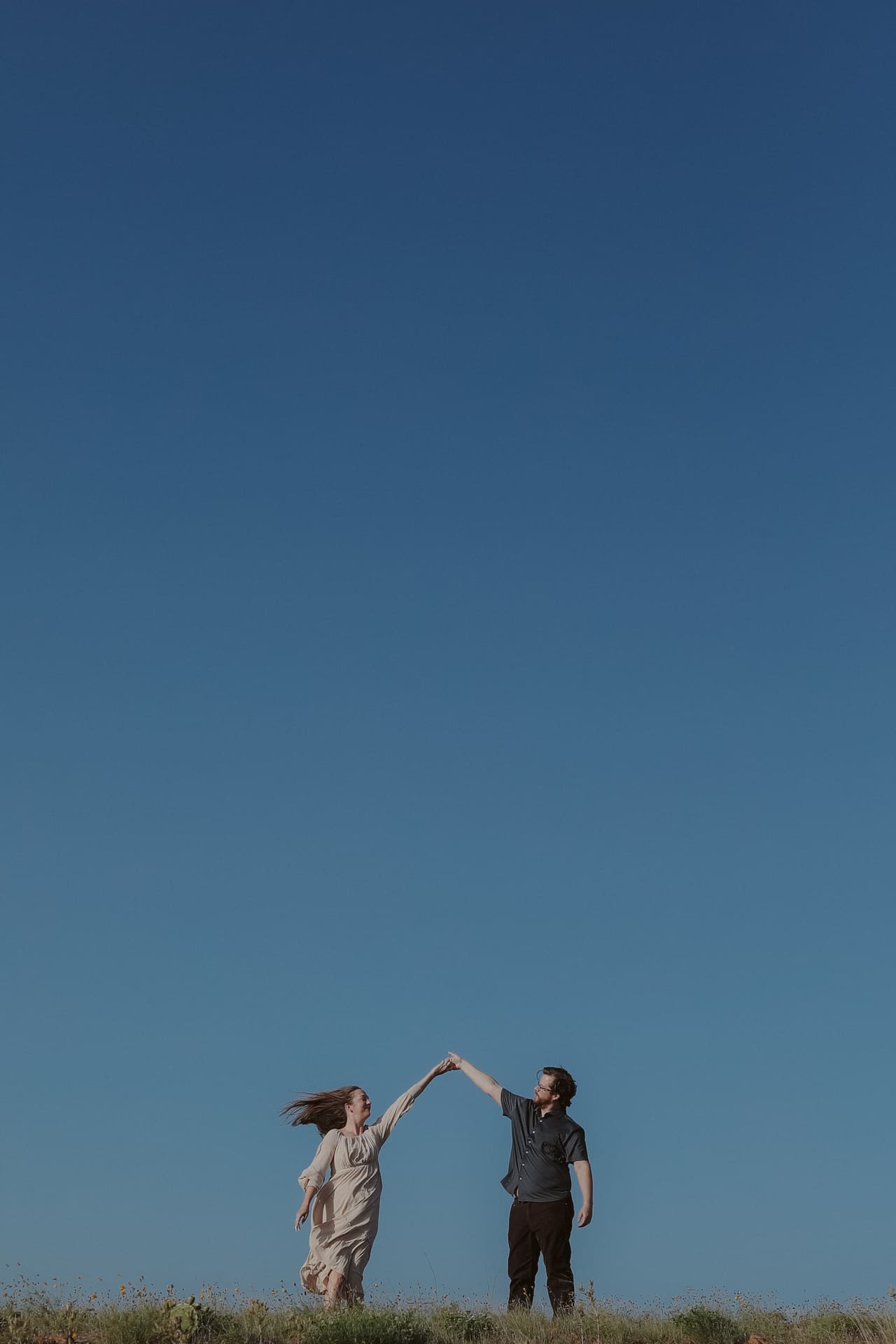 A twirl on the ridgeline, hands raised against the blue