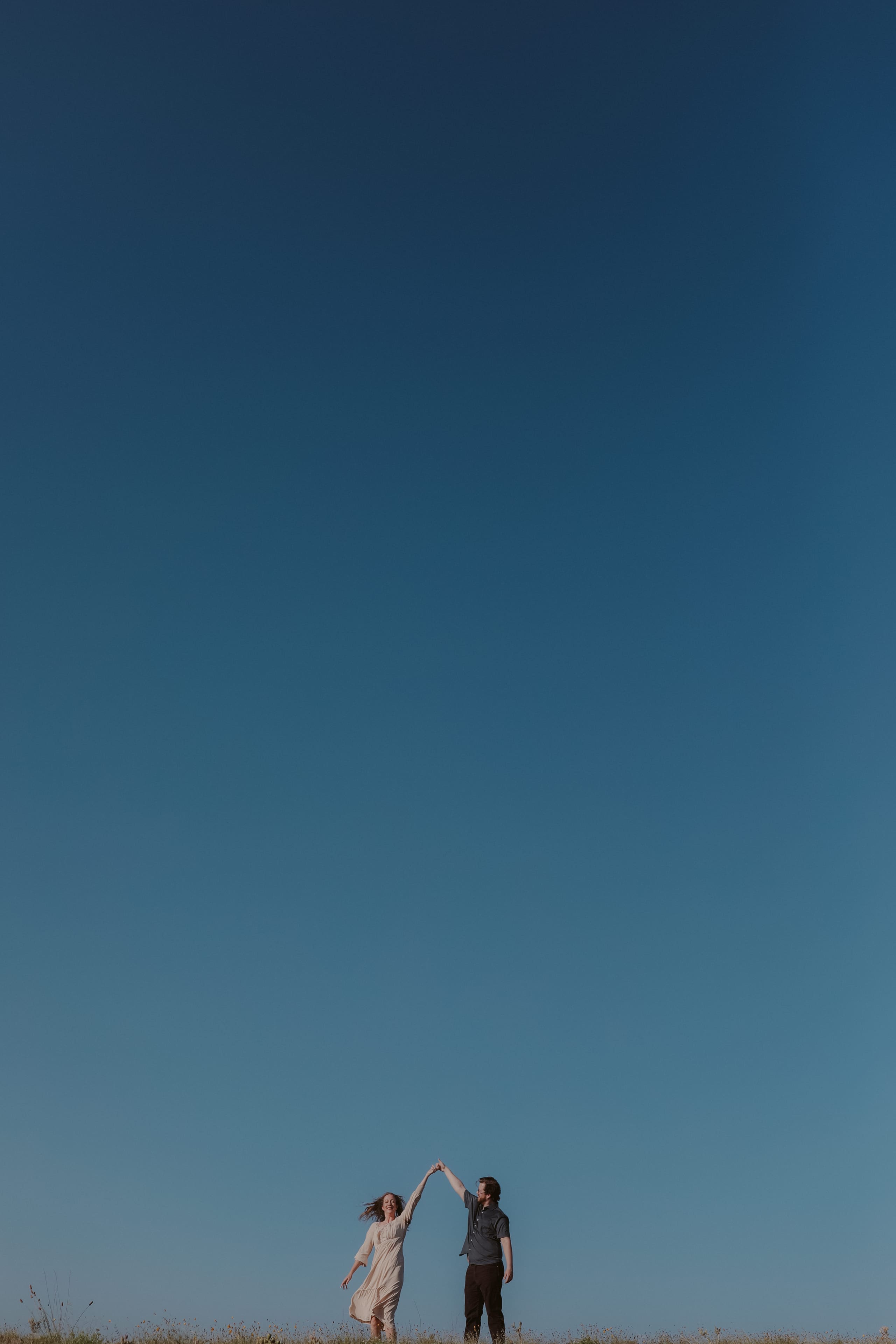 A twirl on the ridgeline, two small figures under a vast blue sky
