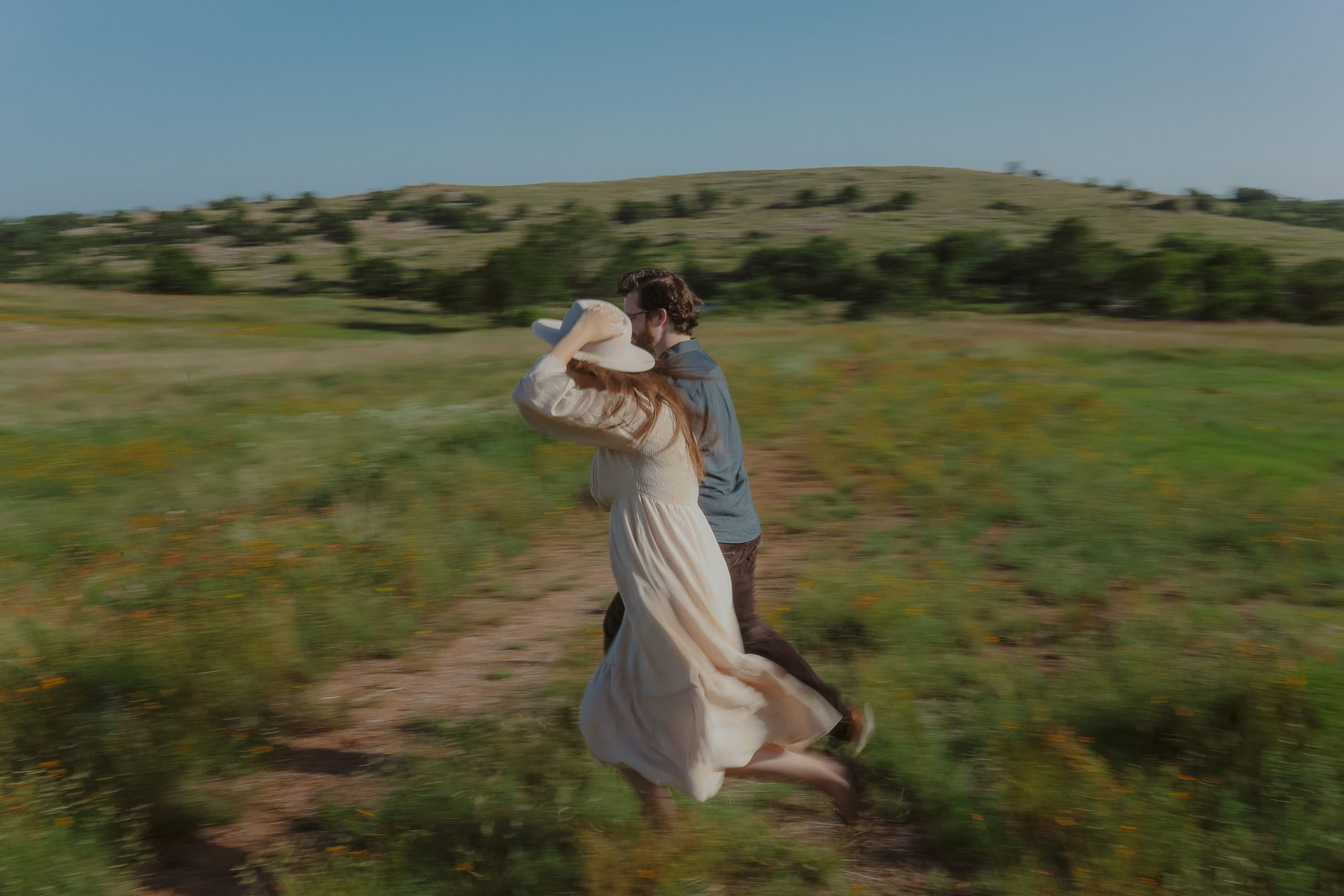 Running through the field in a blur, her hand holding the hat on