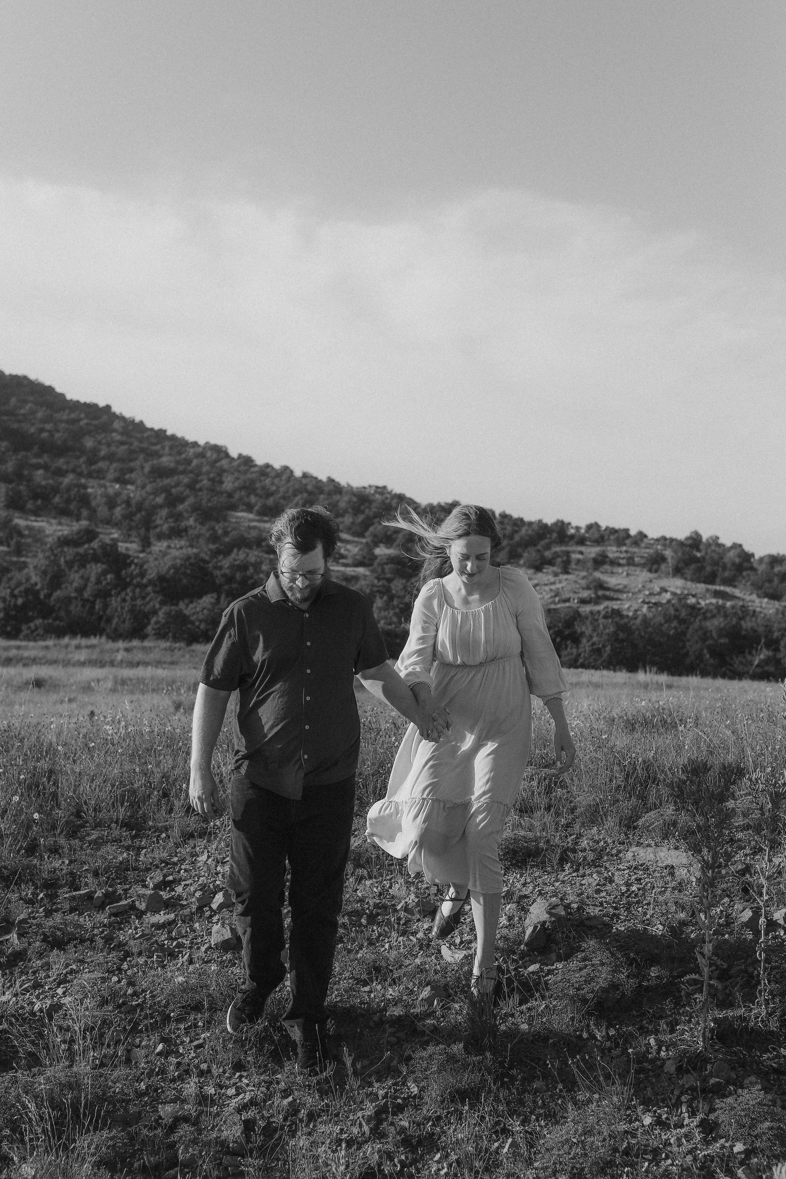 A black-and-white walk hand in hand across the rocky field