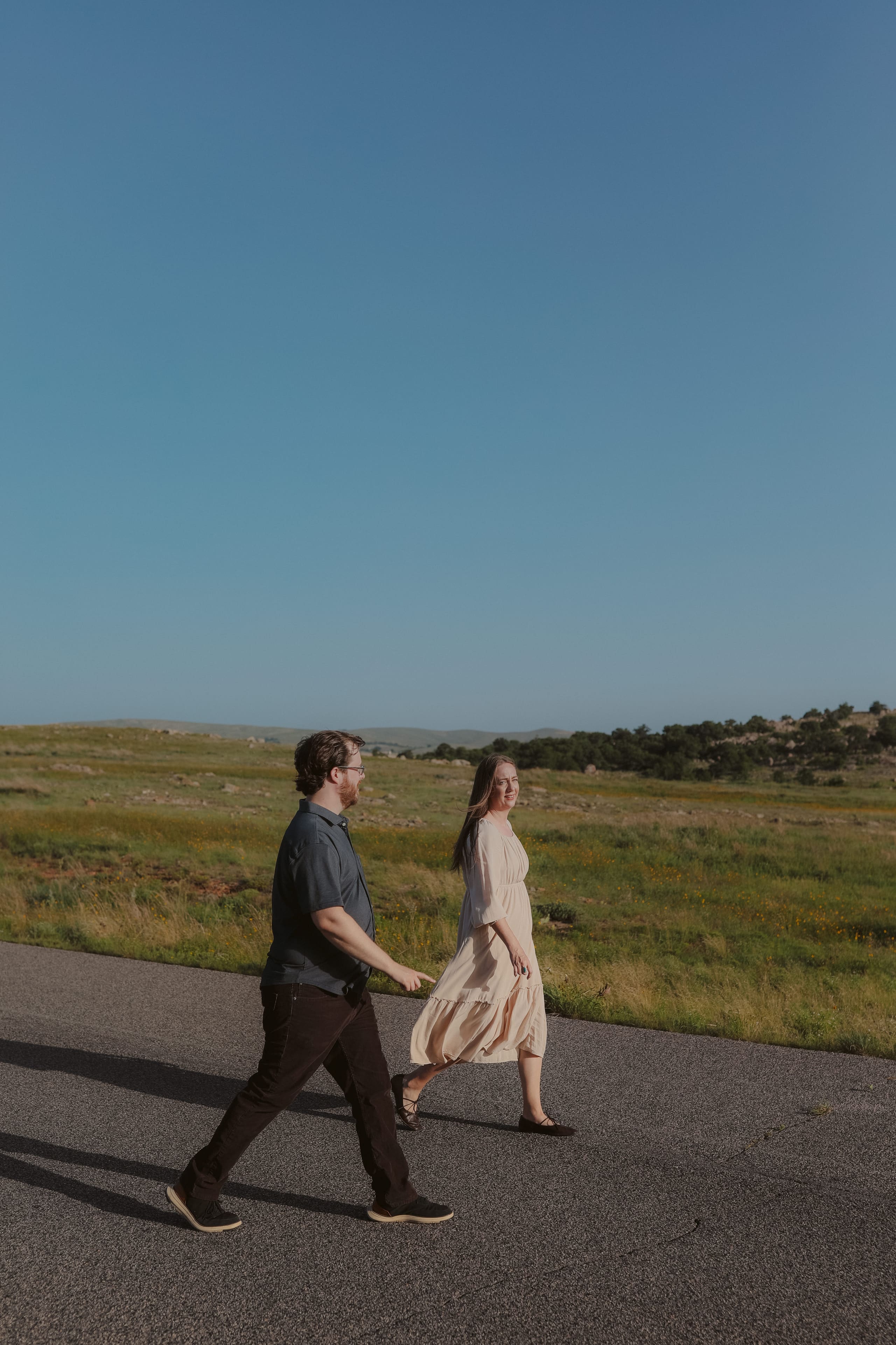 Striding along the road together, wildflower prairie behind