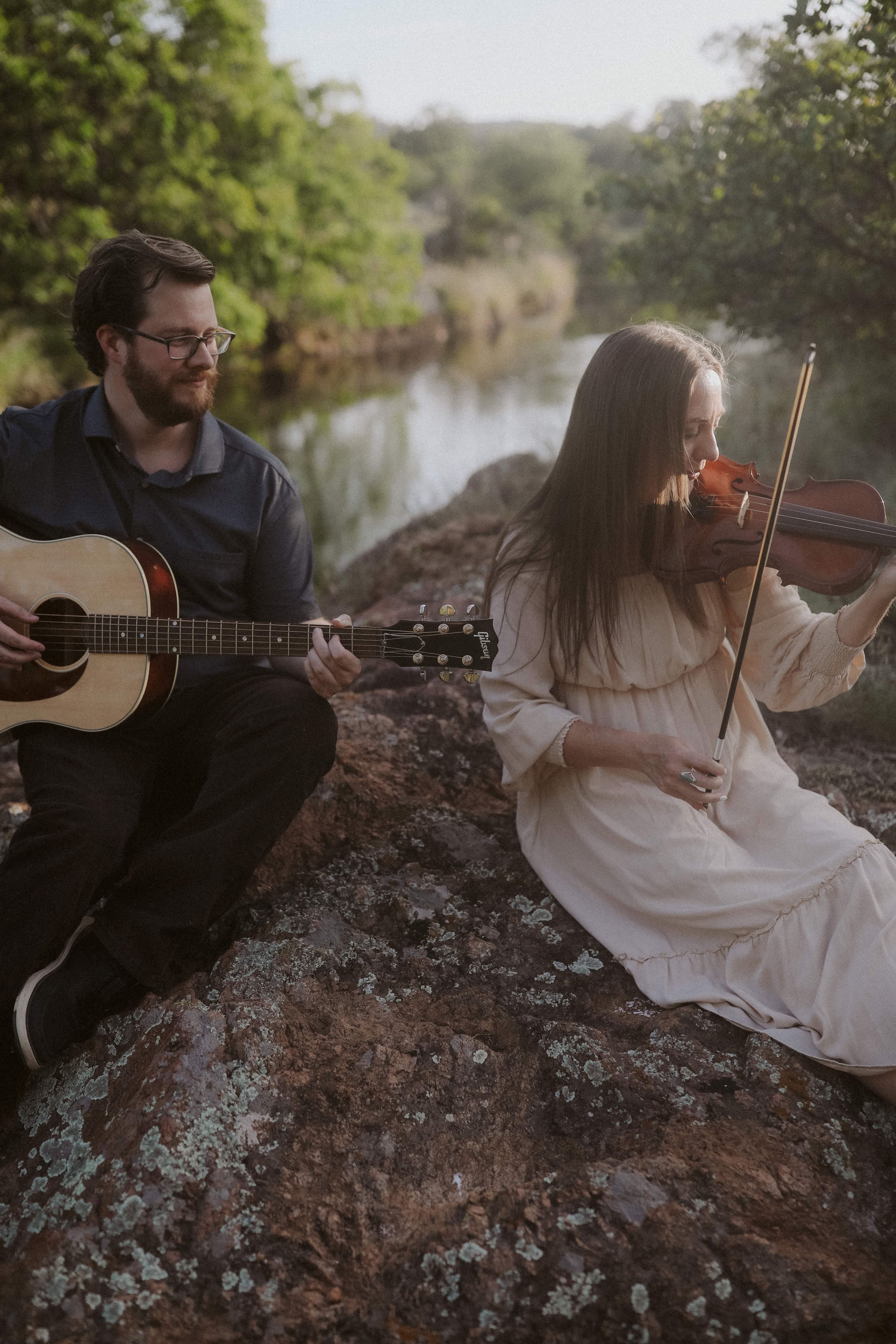 Guitar and violin together on the rocks above the river