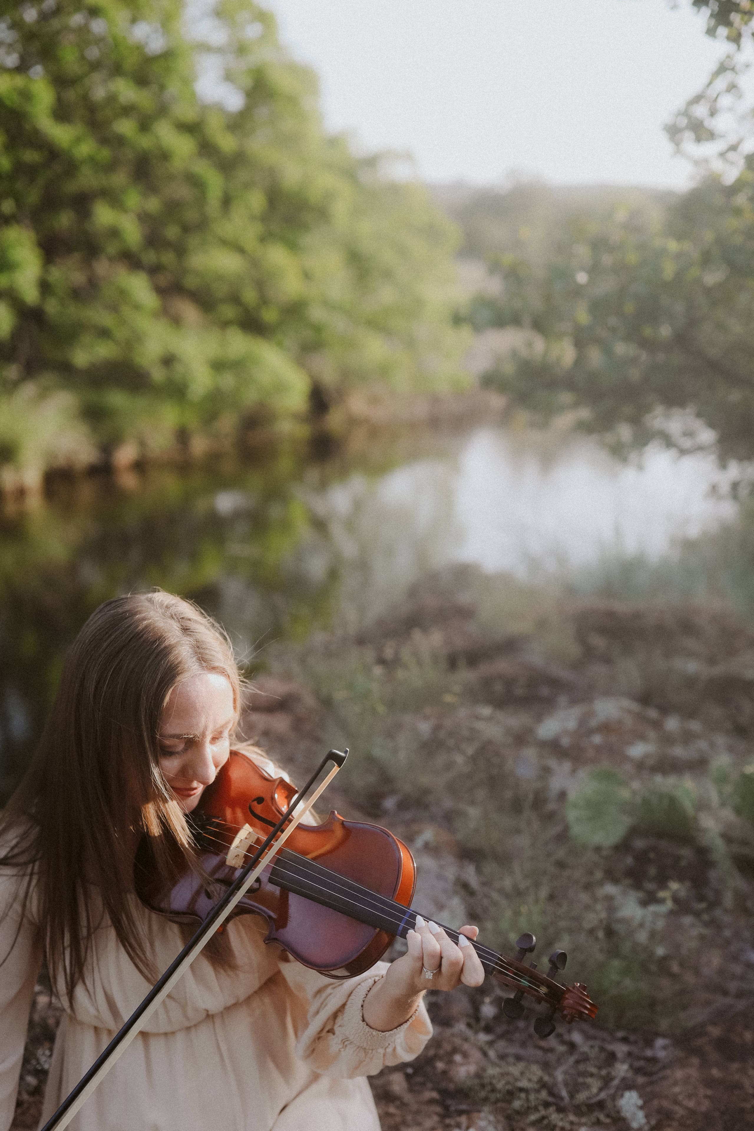 Violin raised by the still water, evening light in the trees