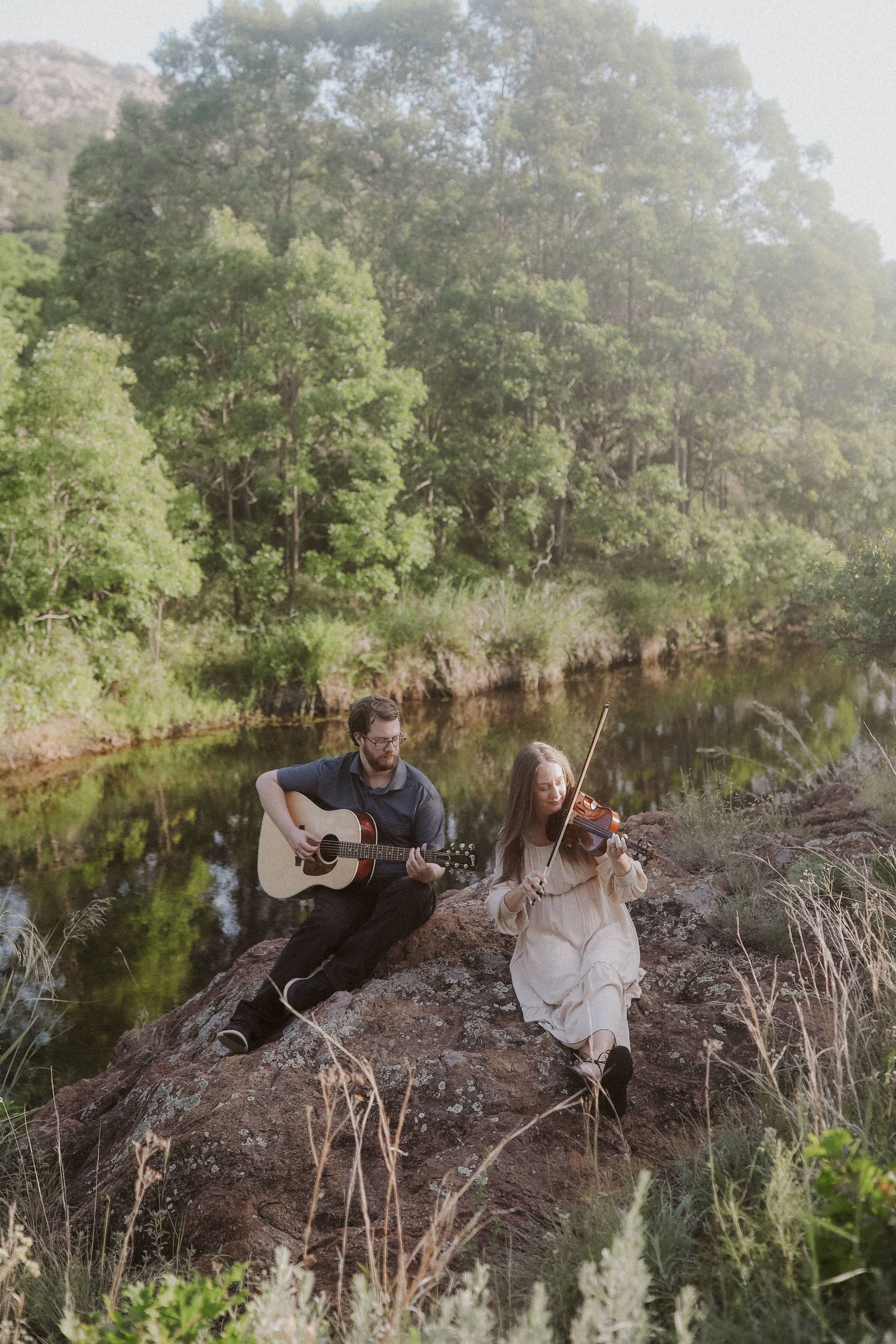 Music on the rocks above the river, trees glowing in the light