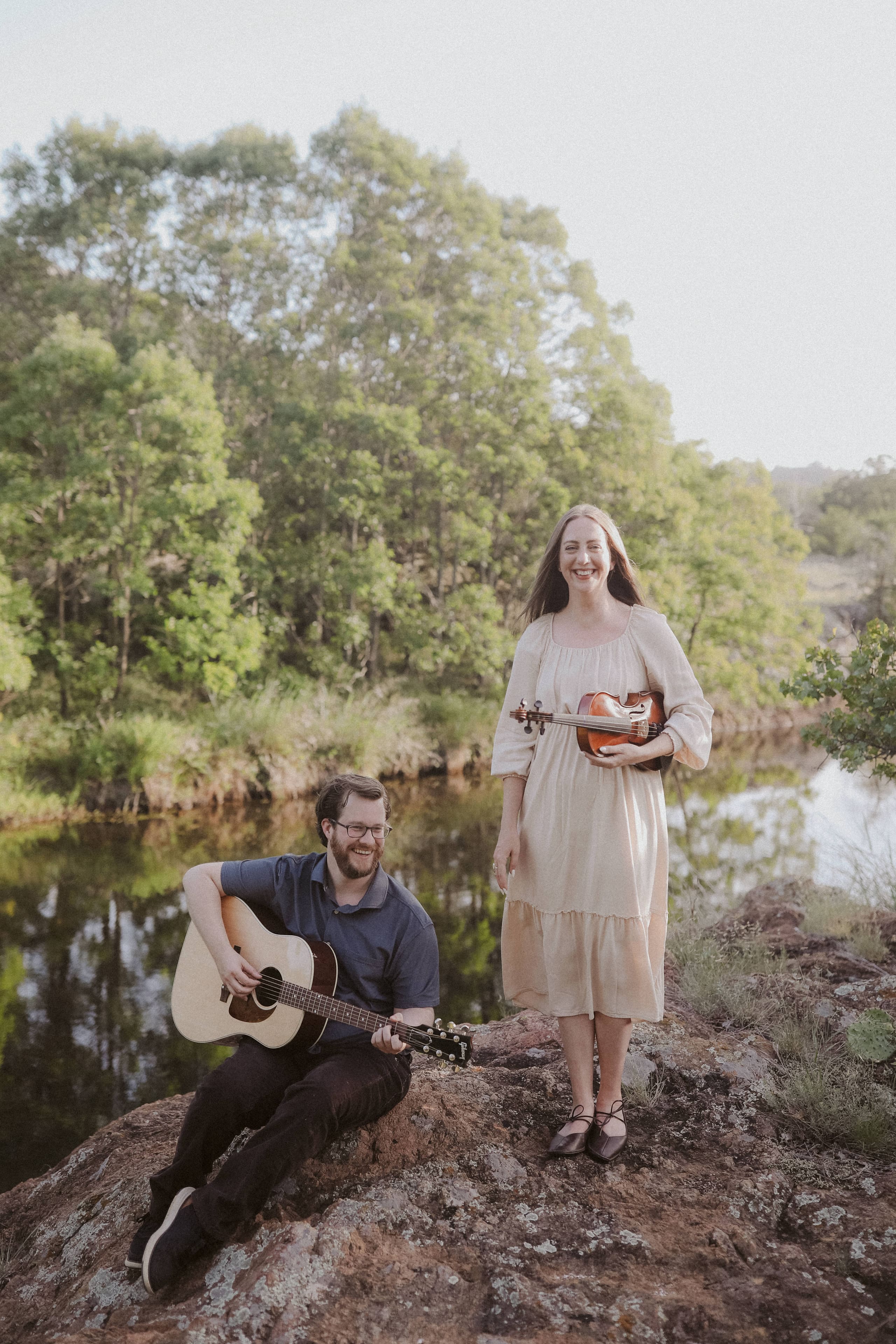 Sharing a laugh with guitar and violin in hand on the riverside rocks
