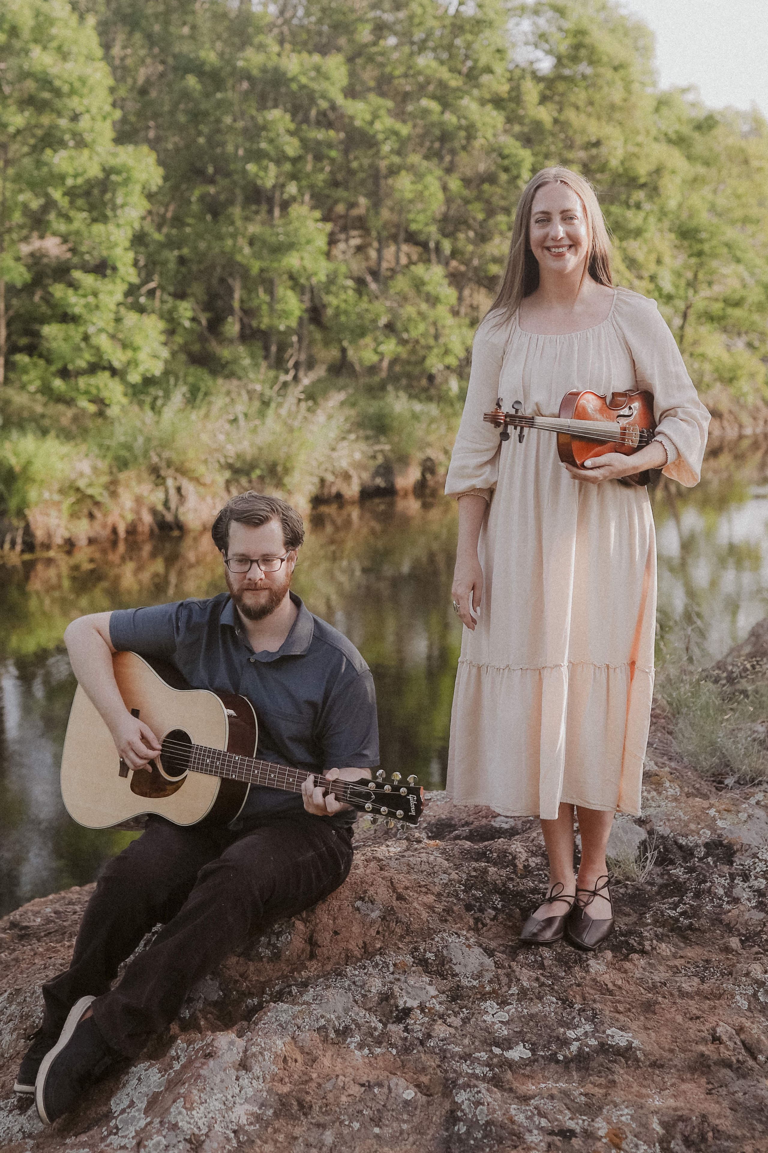 A portrait with guitar and violin on the rocks by the river