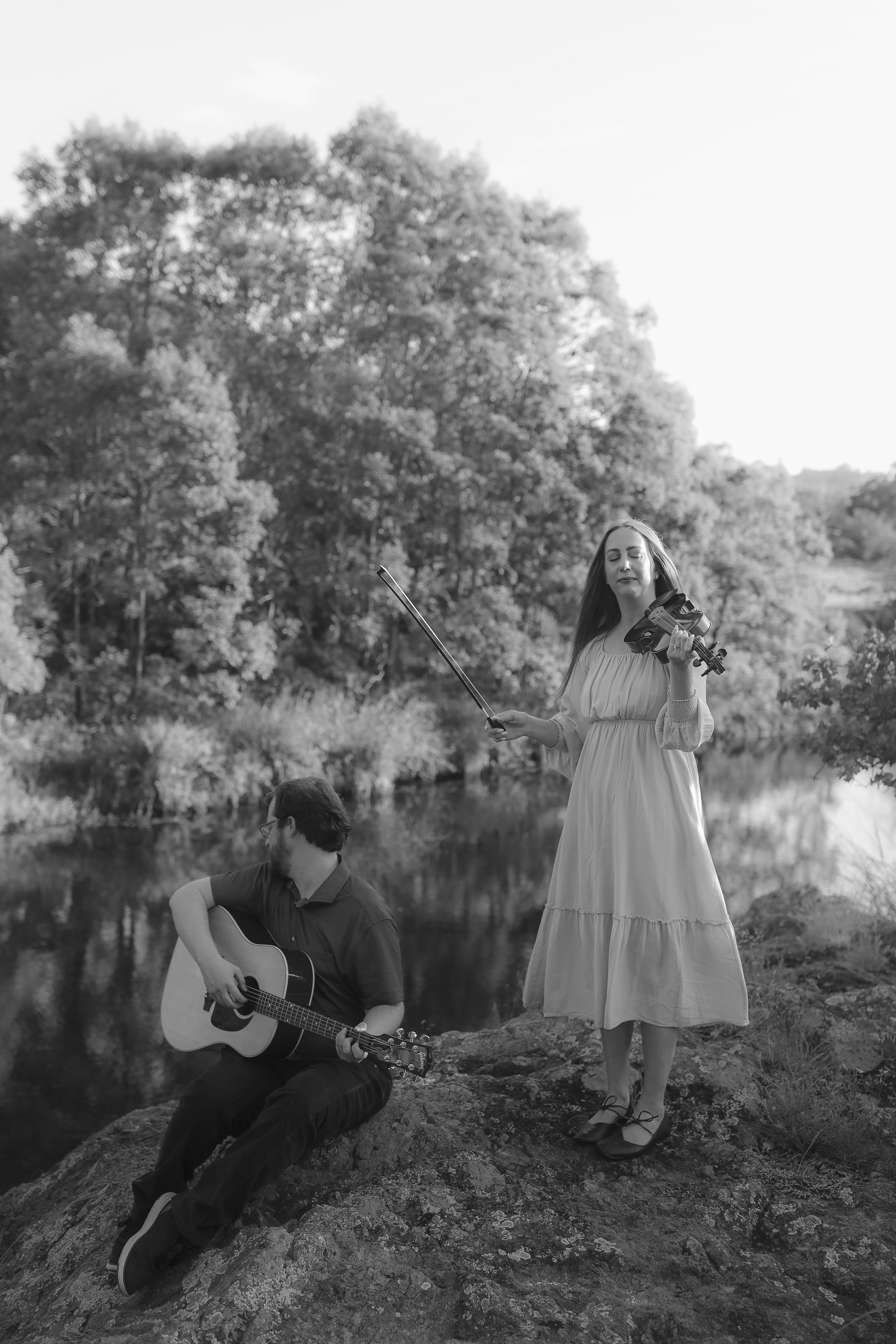Bow raised mid-song at the river’s edge, eyes closed