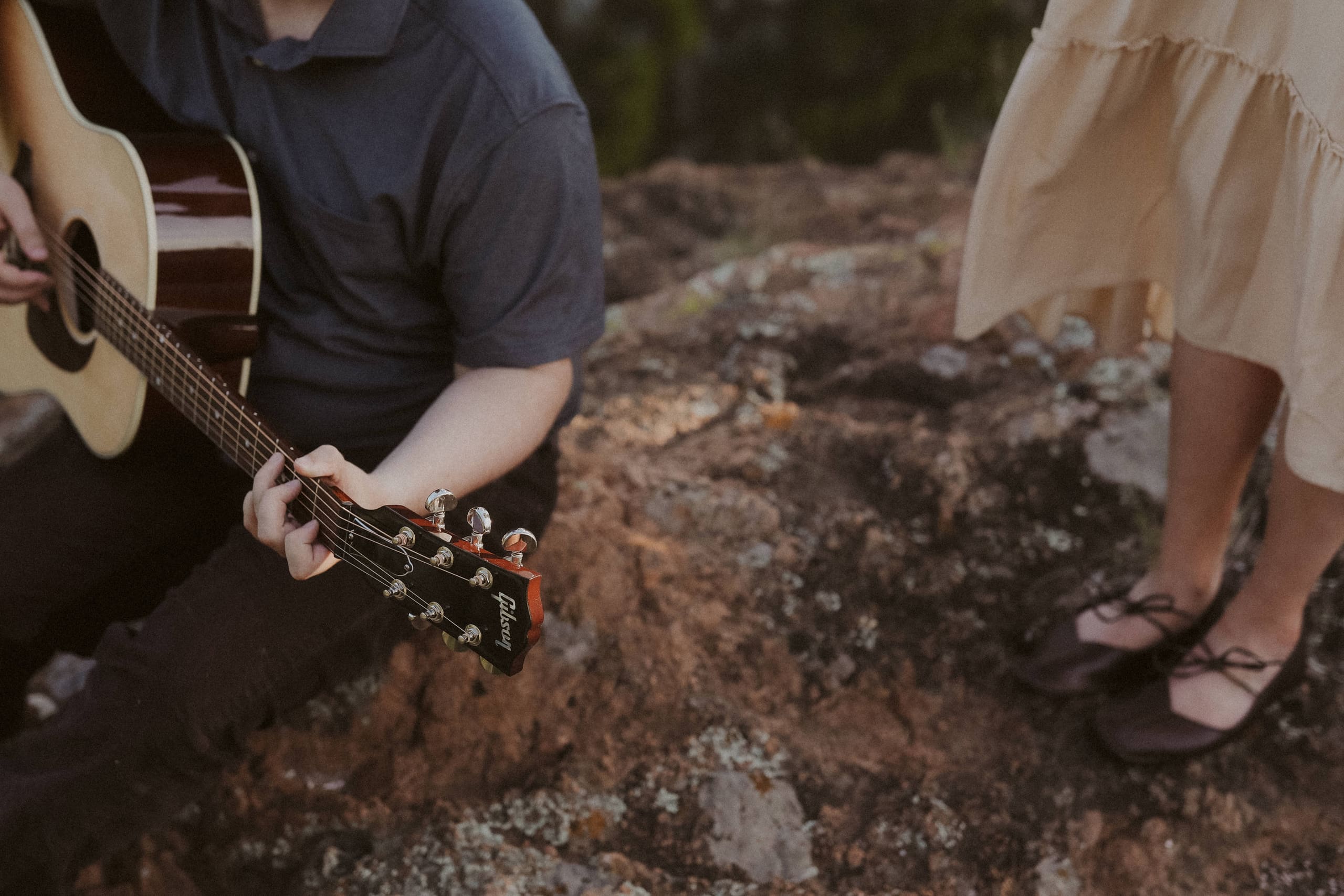 A close-up of guitar strings and her flats on the lichen-covered rock