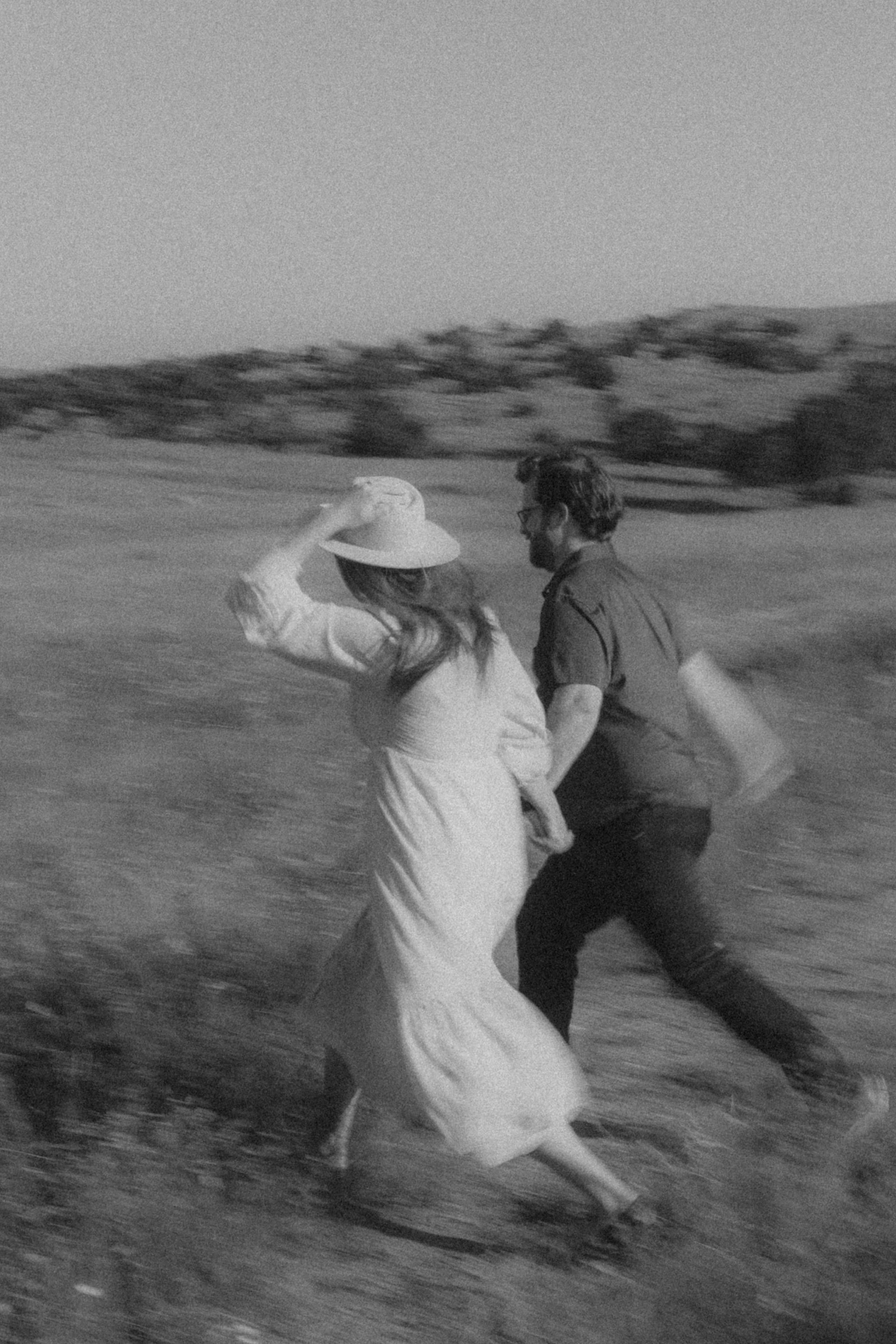 A blurred black-and-white dash through the field, hat held tight