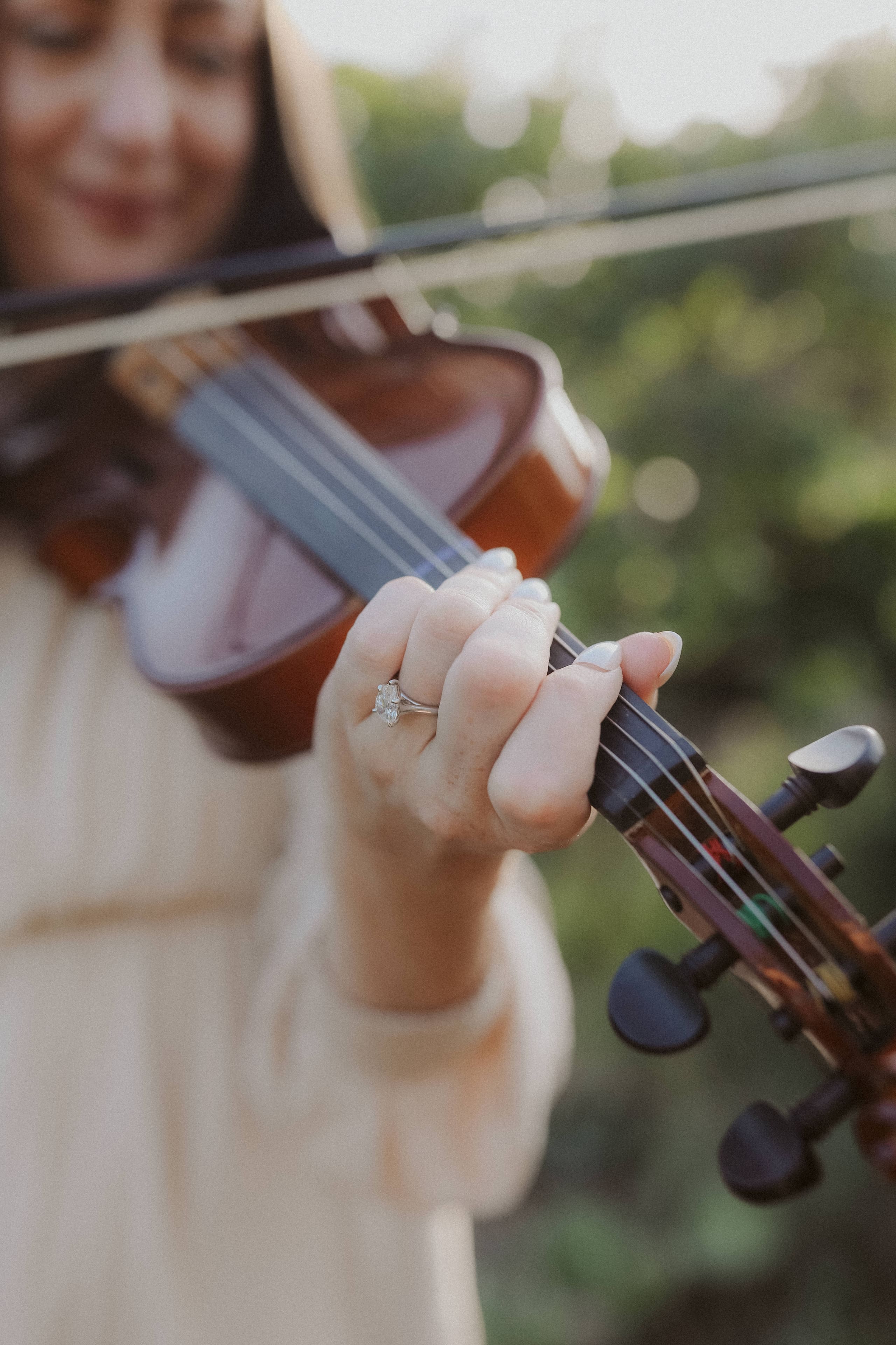 Her engagement ring catching light as her fingers rest on the violin’s neck
