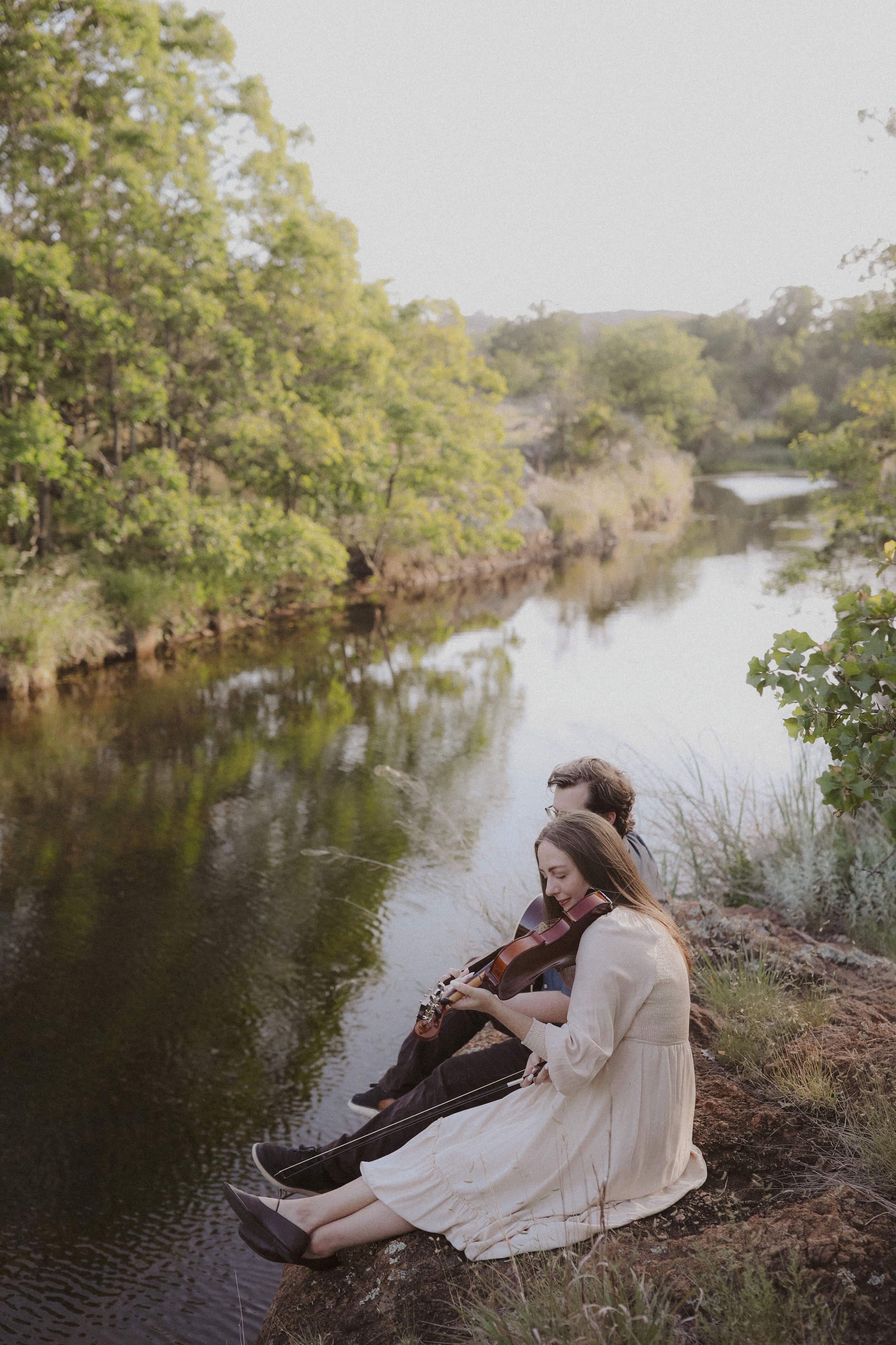 Violin and guitar on the river’s edge above the quiet water