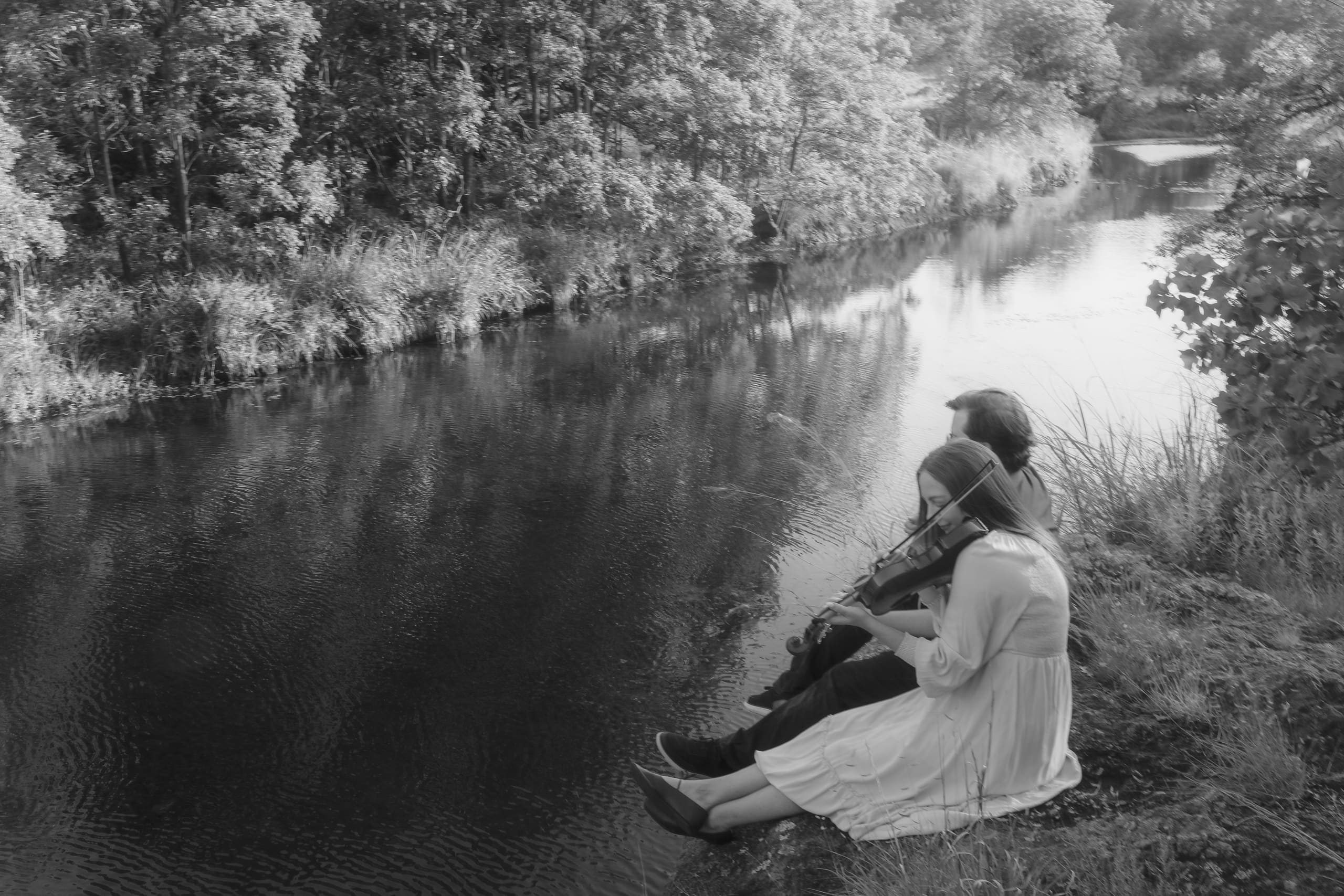 A black-and-white view of the two playing together above the still river