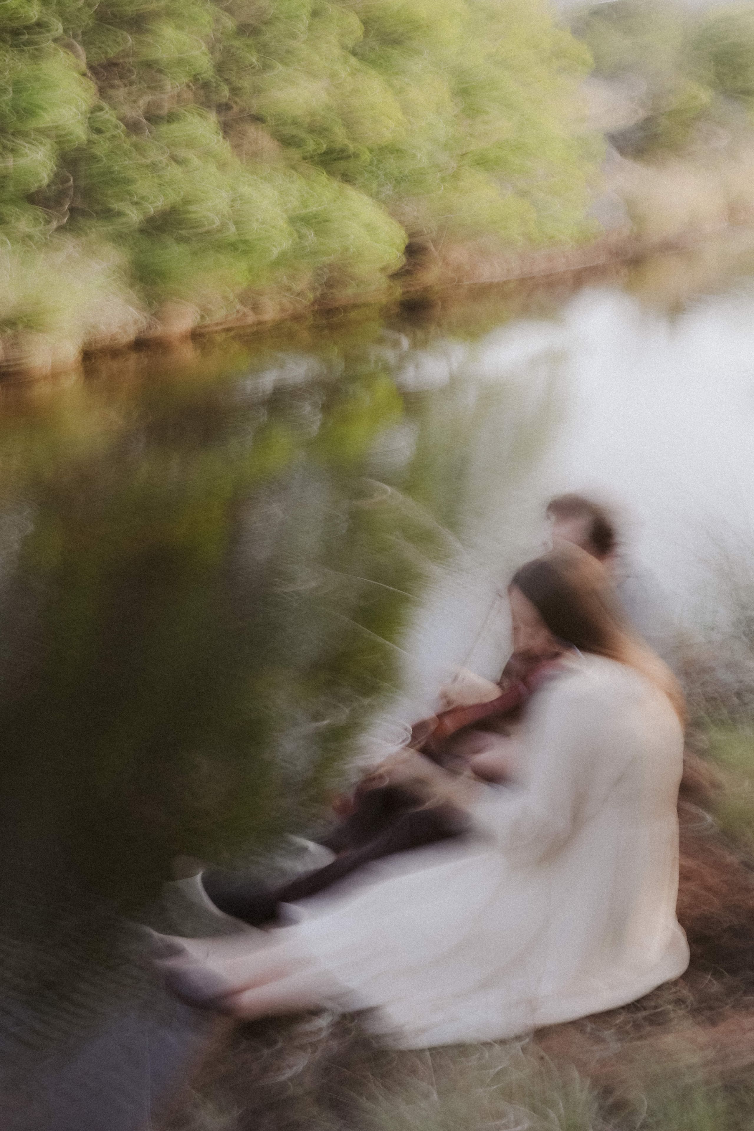 A dreamlike blur — her white dress and violin dissolving into the riverbank