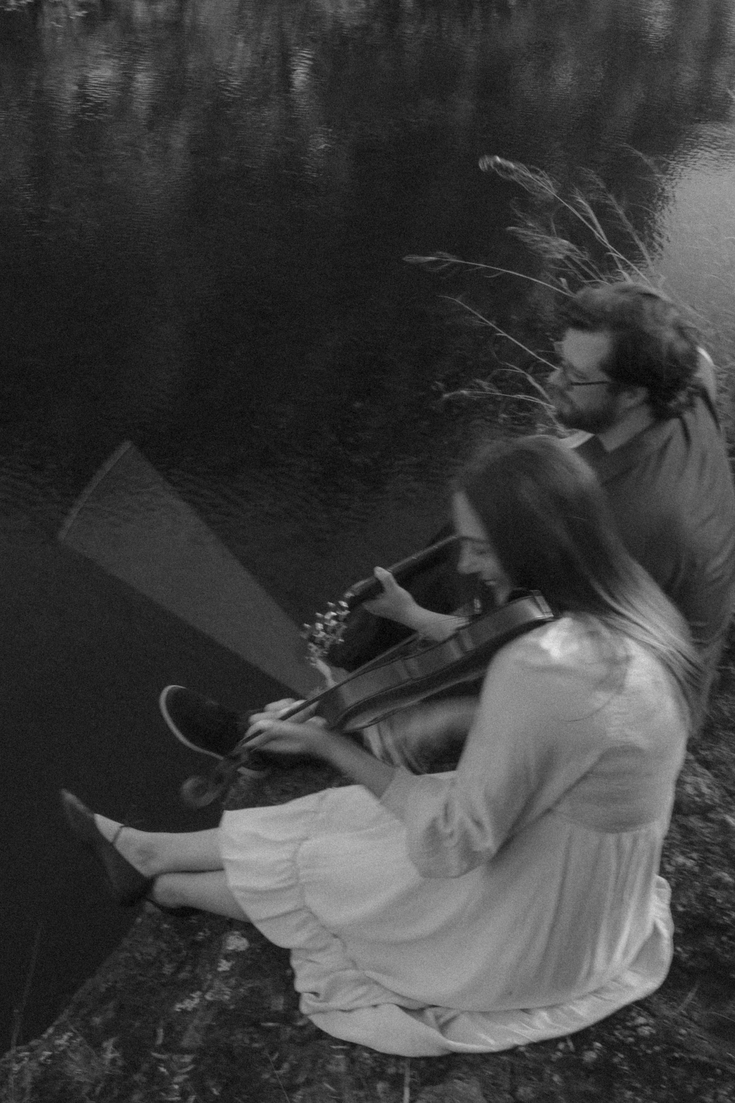 From above in black and white, bow and strings beside the darkened river