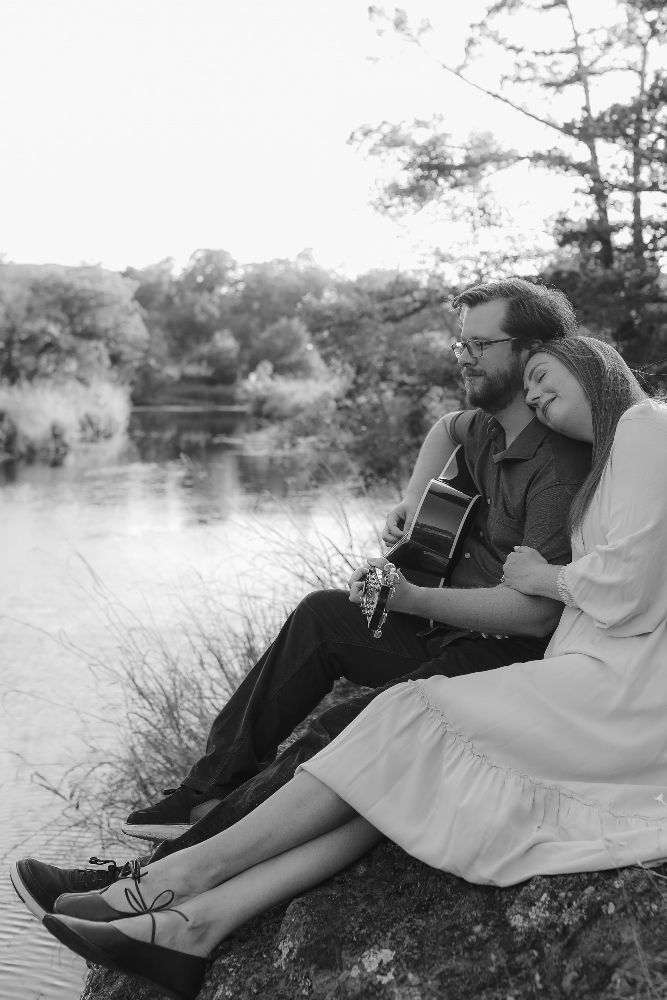 Her head on his shoulder as he plays, the river quiet below