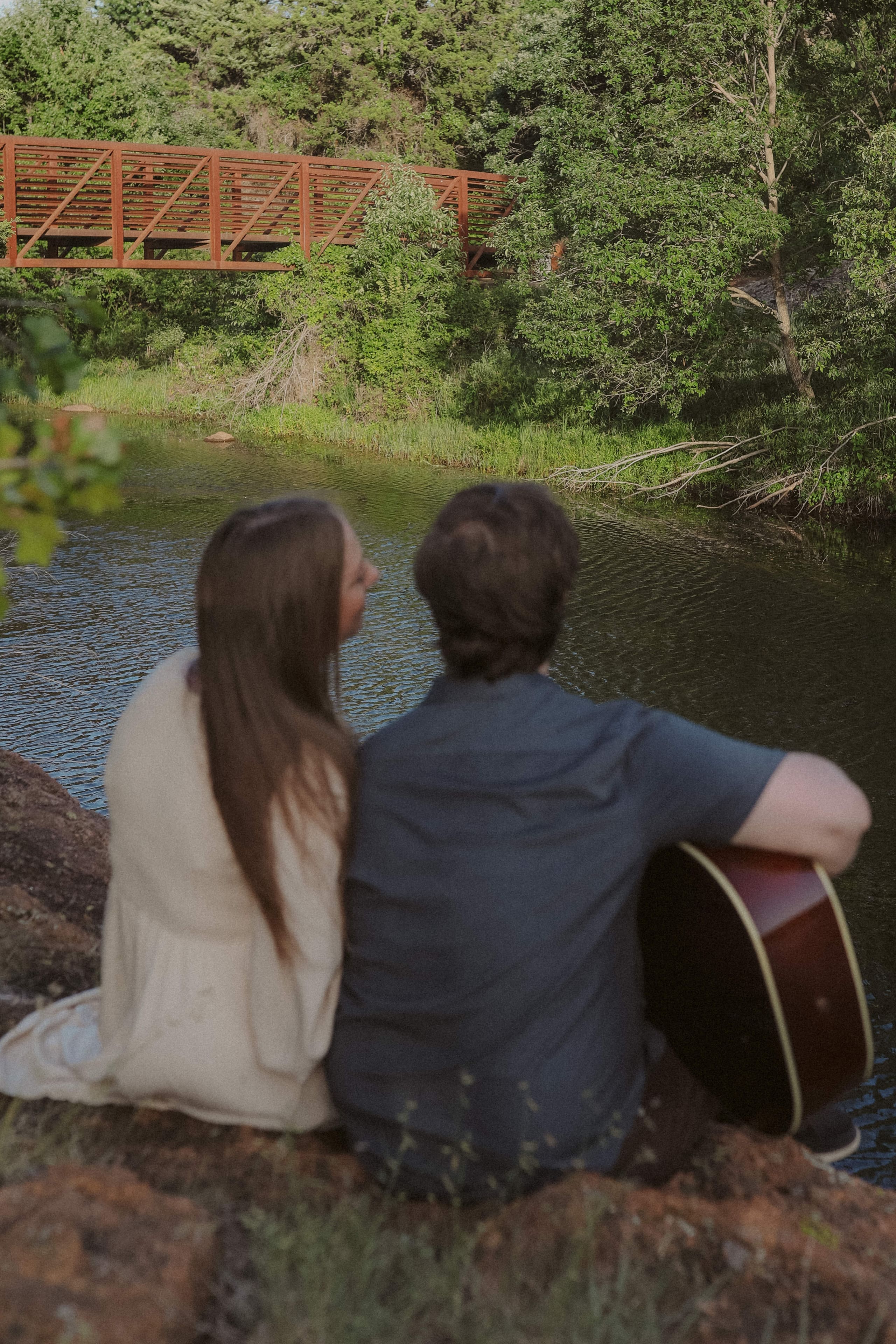 Looking out toward the footbridge together, guitar tucked at his side