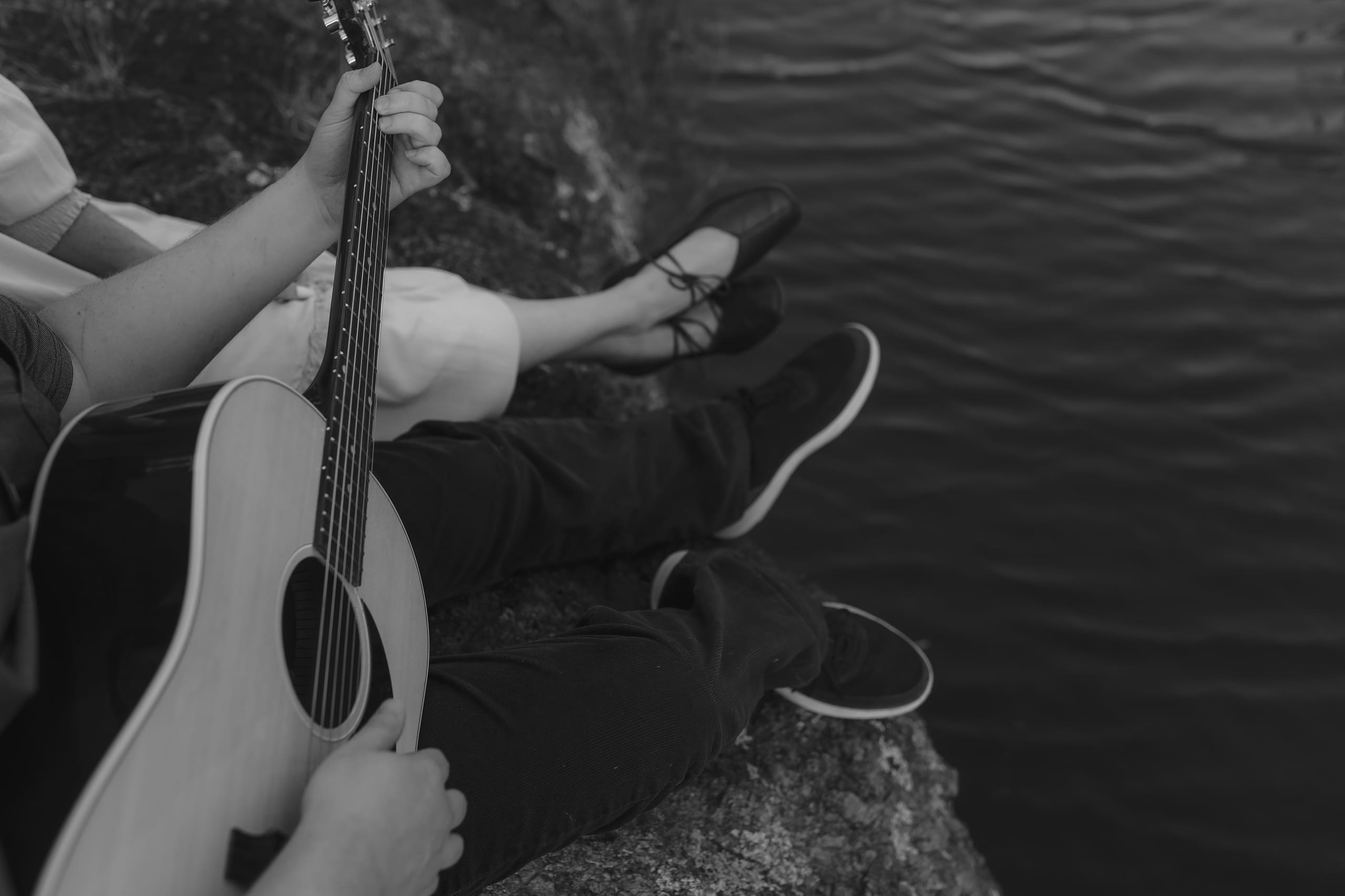 Guitar strings and dangling feet in black and white above the ripples