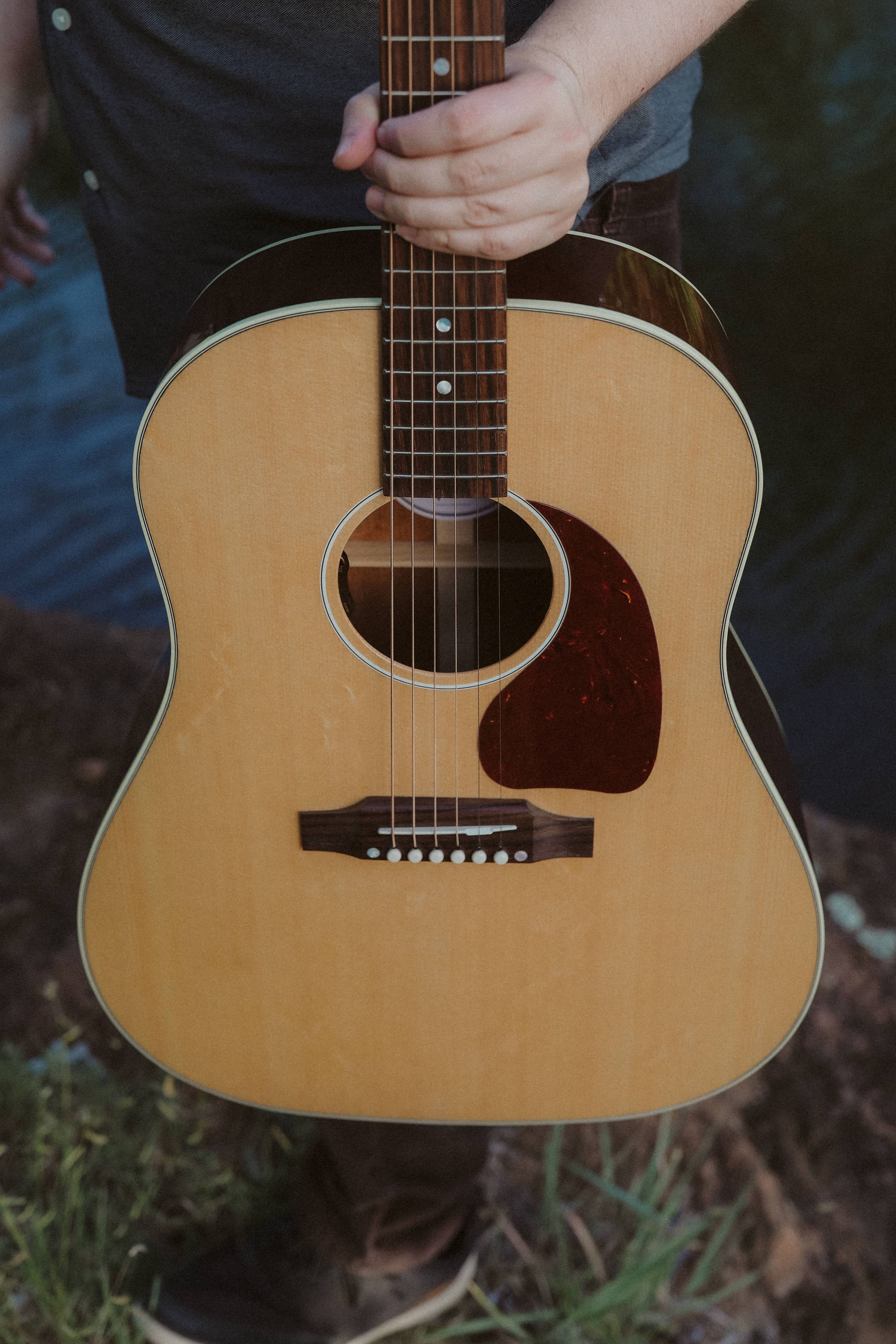 The guitar held up close, warm wood against the evening shade
