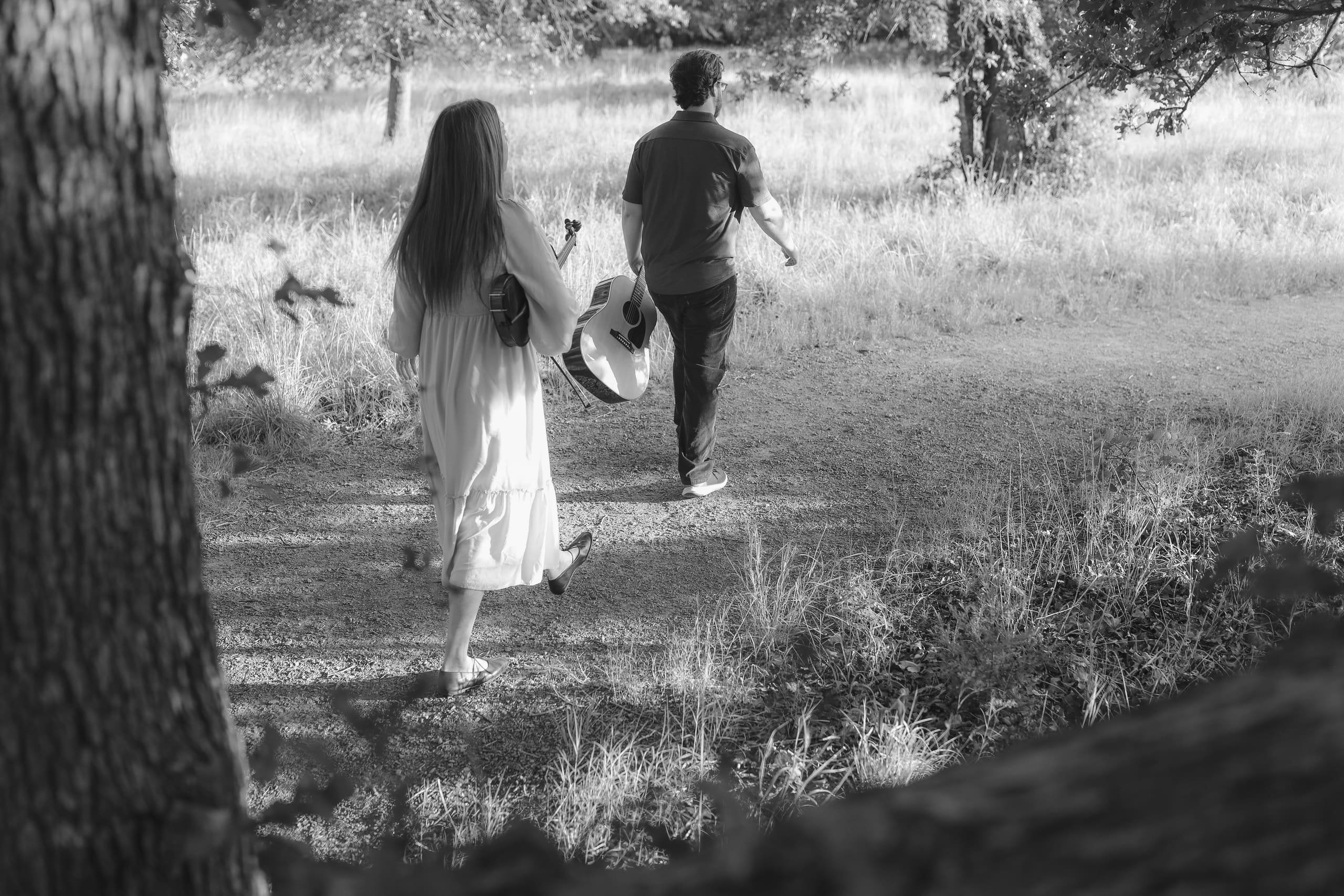 Walking the shaded path with guitar and violin, in black and white