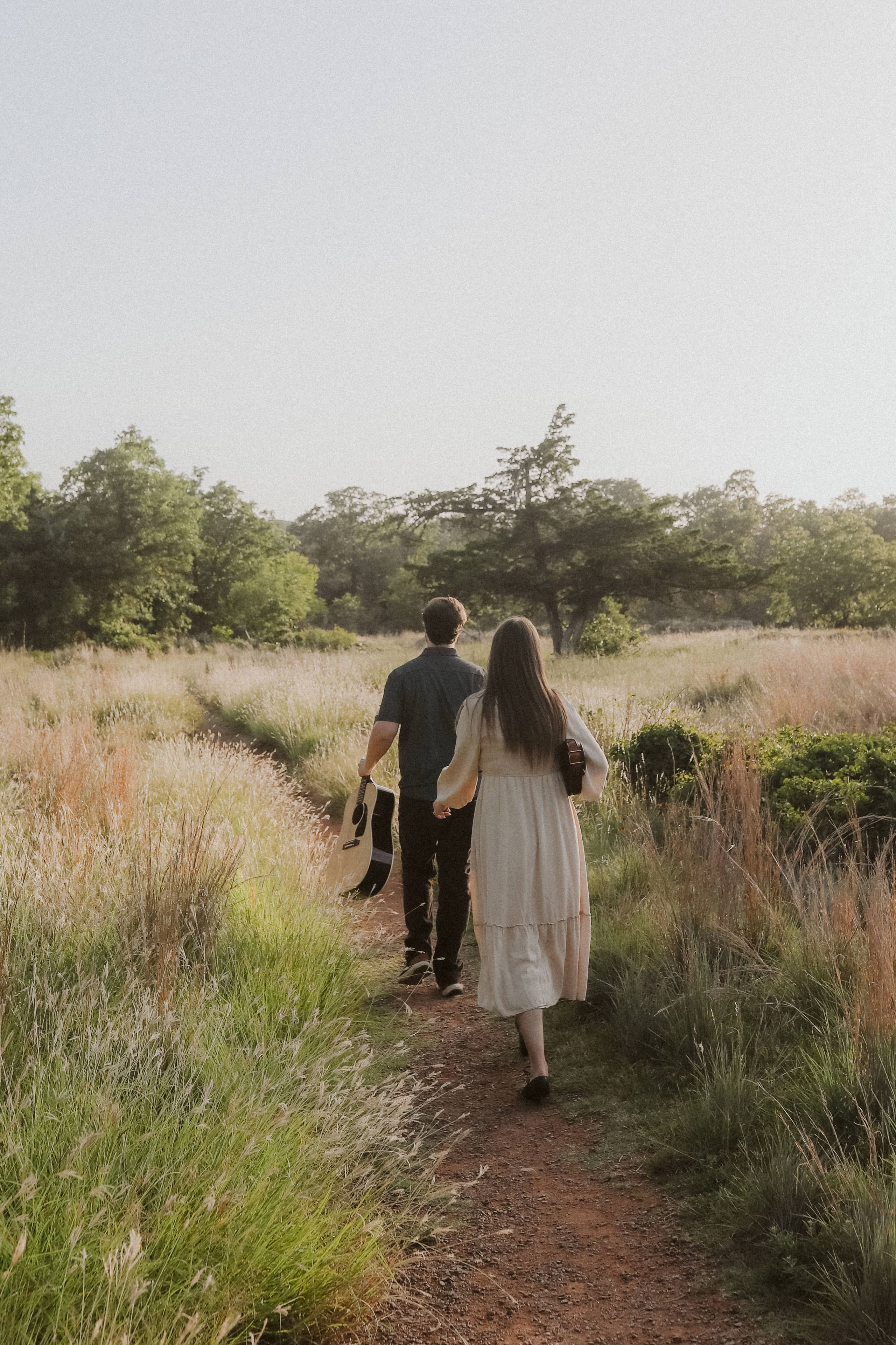 Hand in hand down a golden prairie trail, carrying guitar and violin