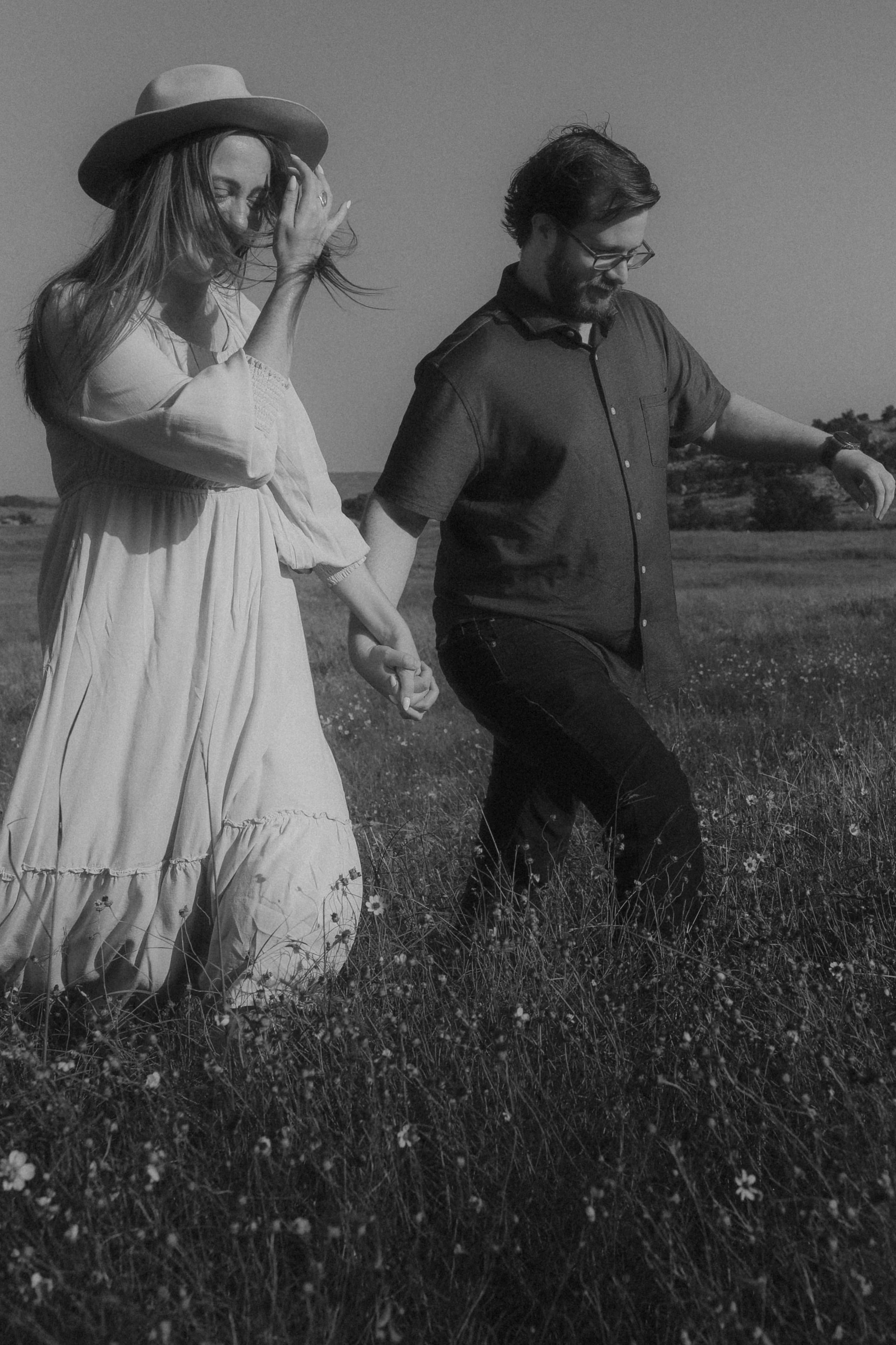 Hand in hand through a wildflower field, wind catching her hair