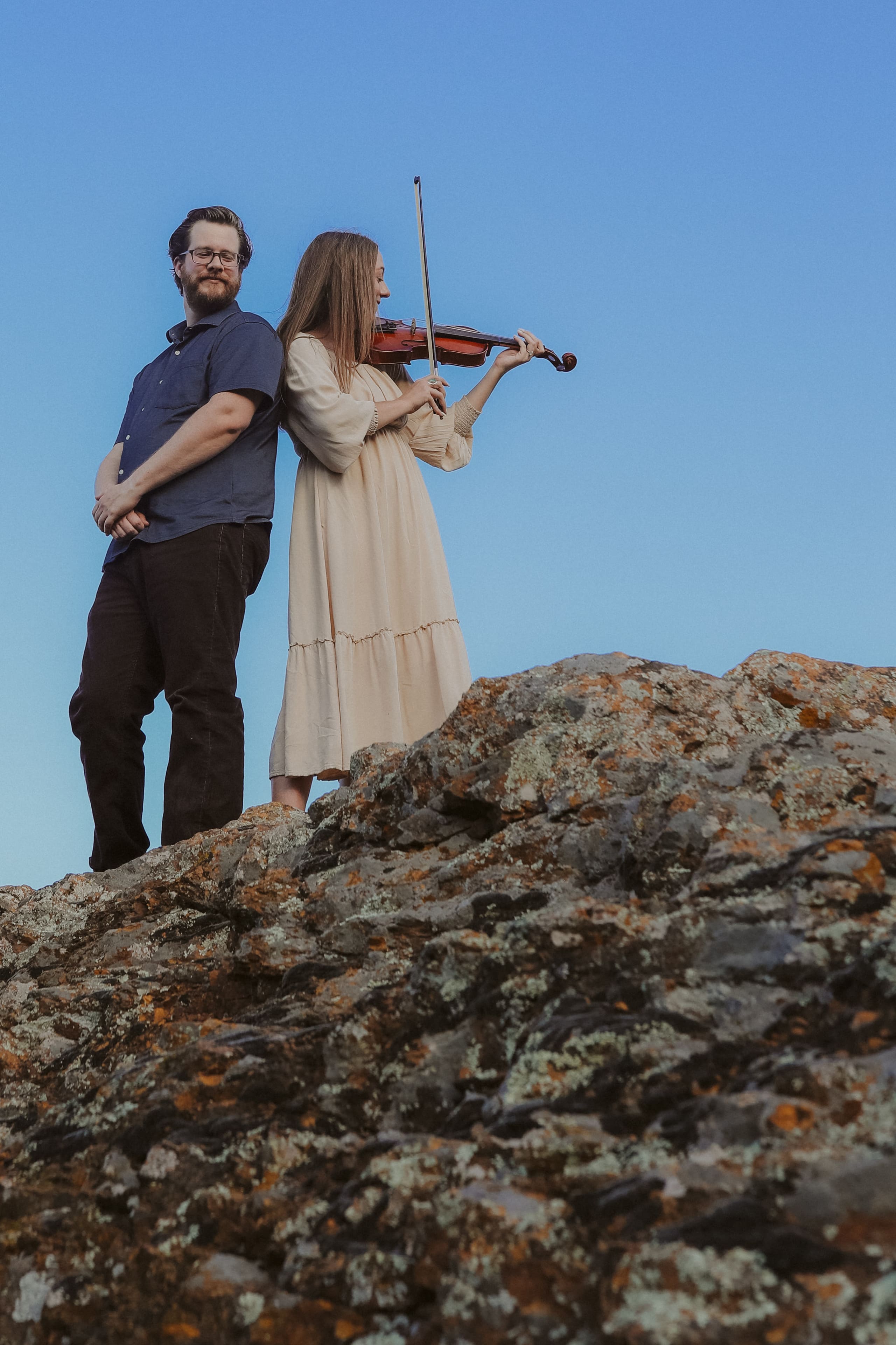Standing on the granite outcrop, violin and guitar against a blue sky