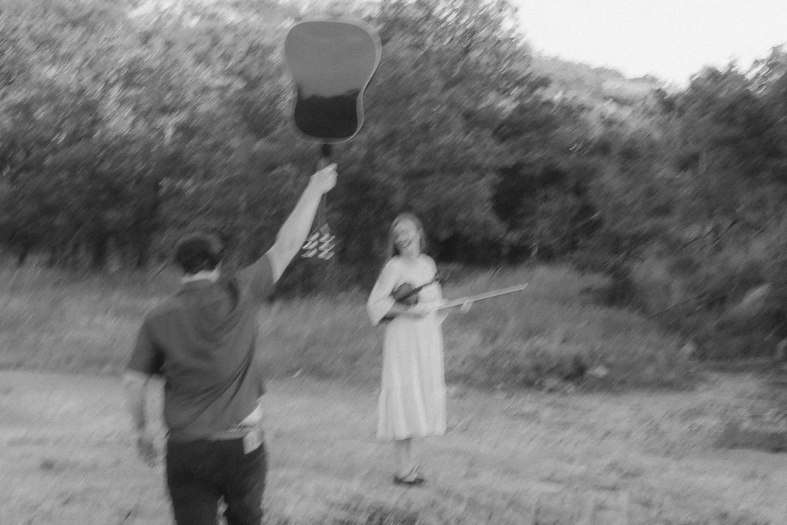 Guitar hoisted overhead while she laughs, violin in hand