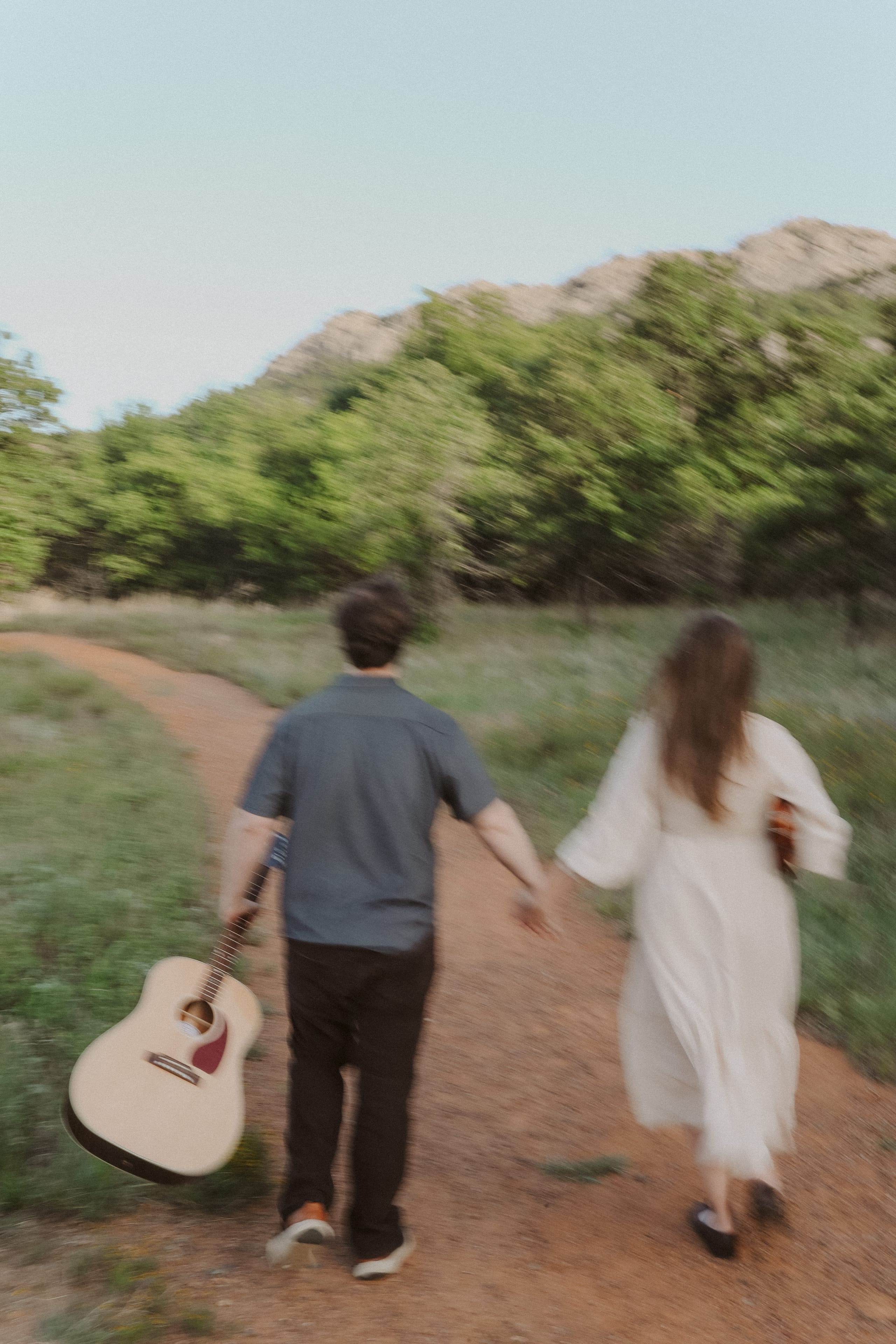 Down the red dirt trail toward the mountain, guitar swinging at his side