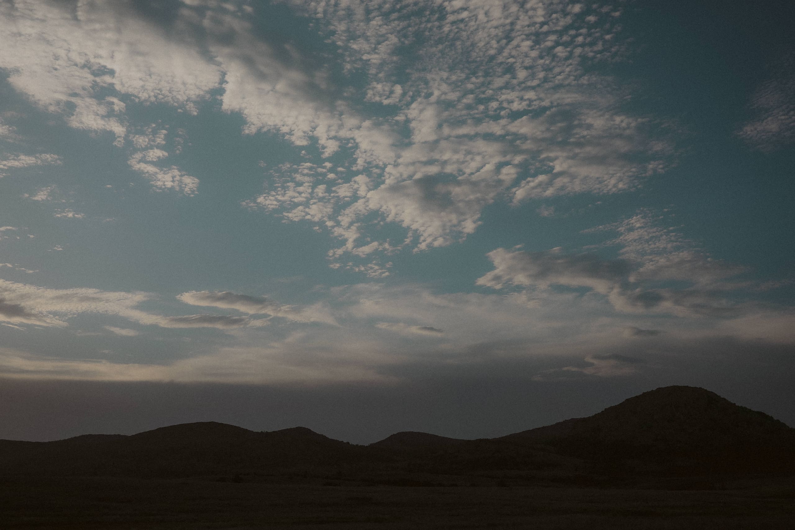 Dappled clouds at dusk over darkened mountain silhouettes