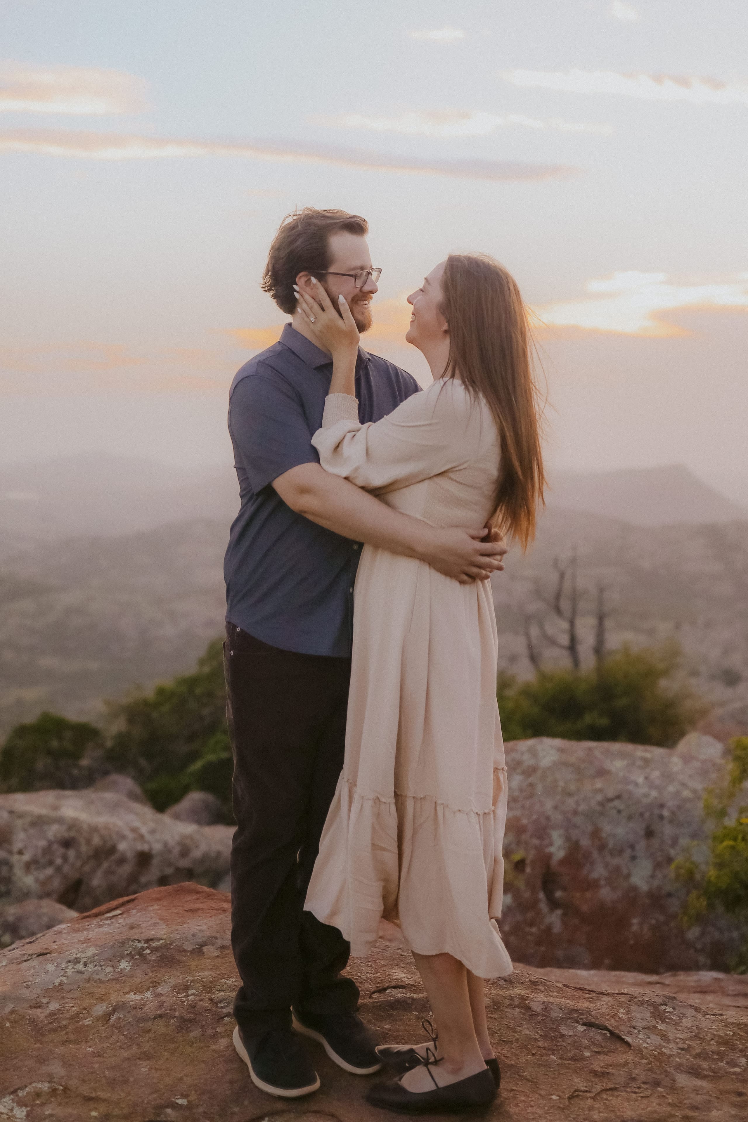 Her hand on his cheek, smiling face to face above the misty valley