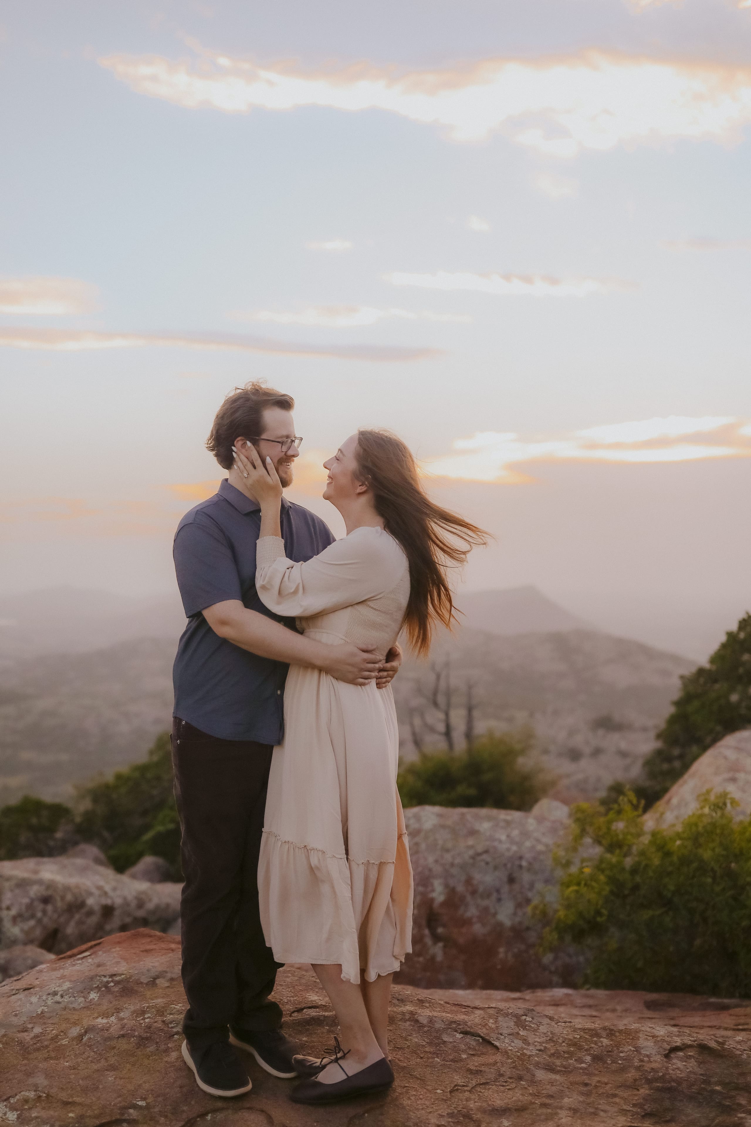 Wrapped in an embrace on the summit, her hair caught in the wind