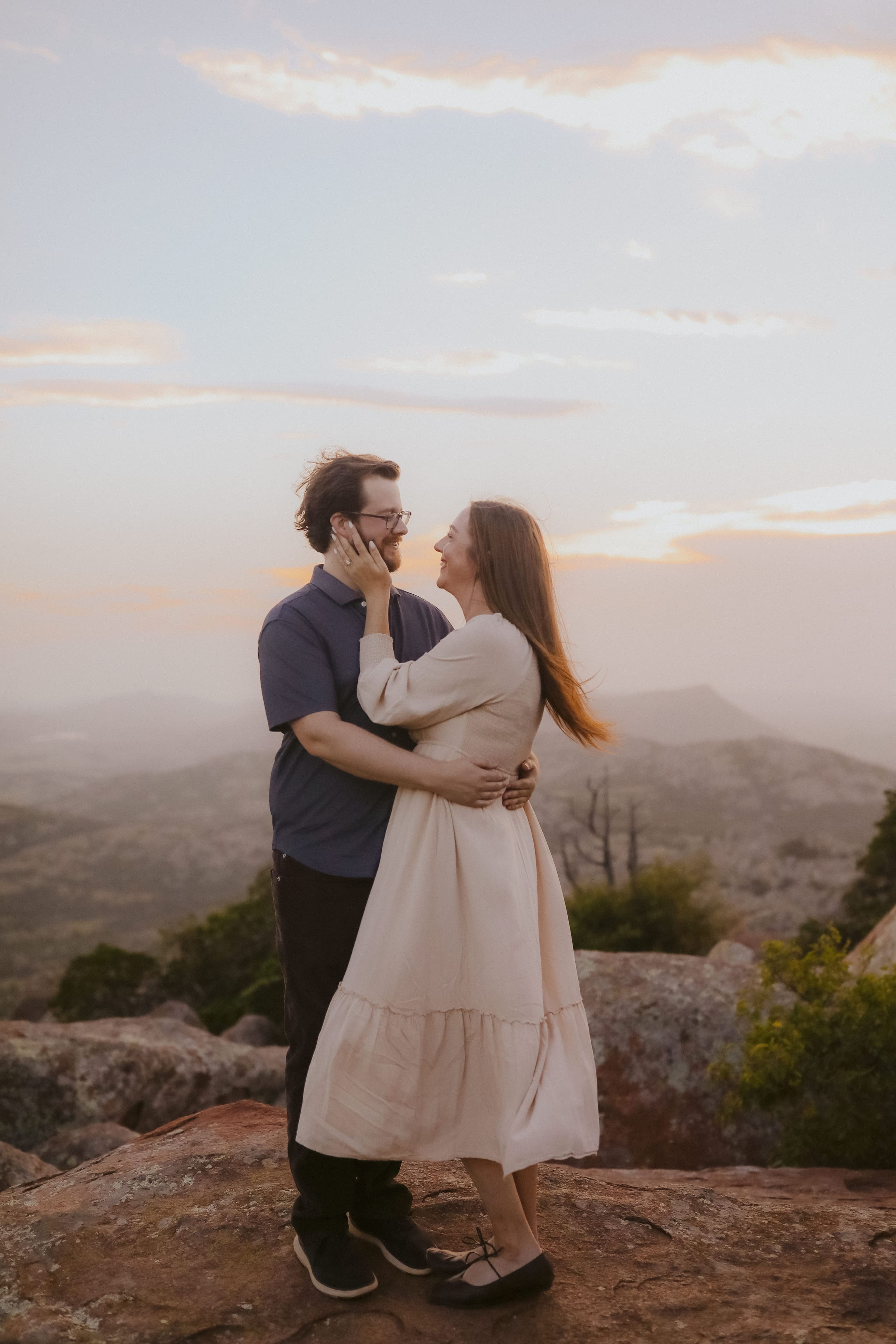 Holding each other close on the summit as the sunset softens the hills