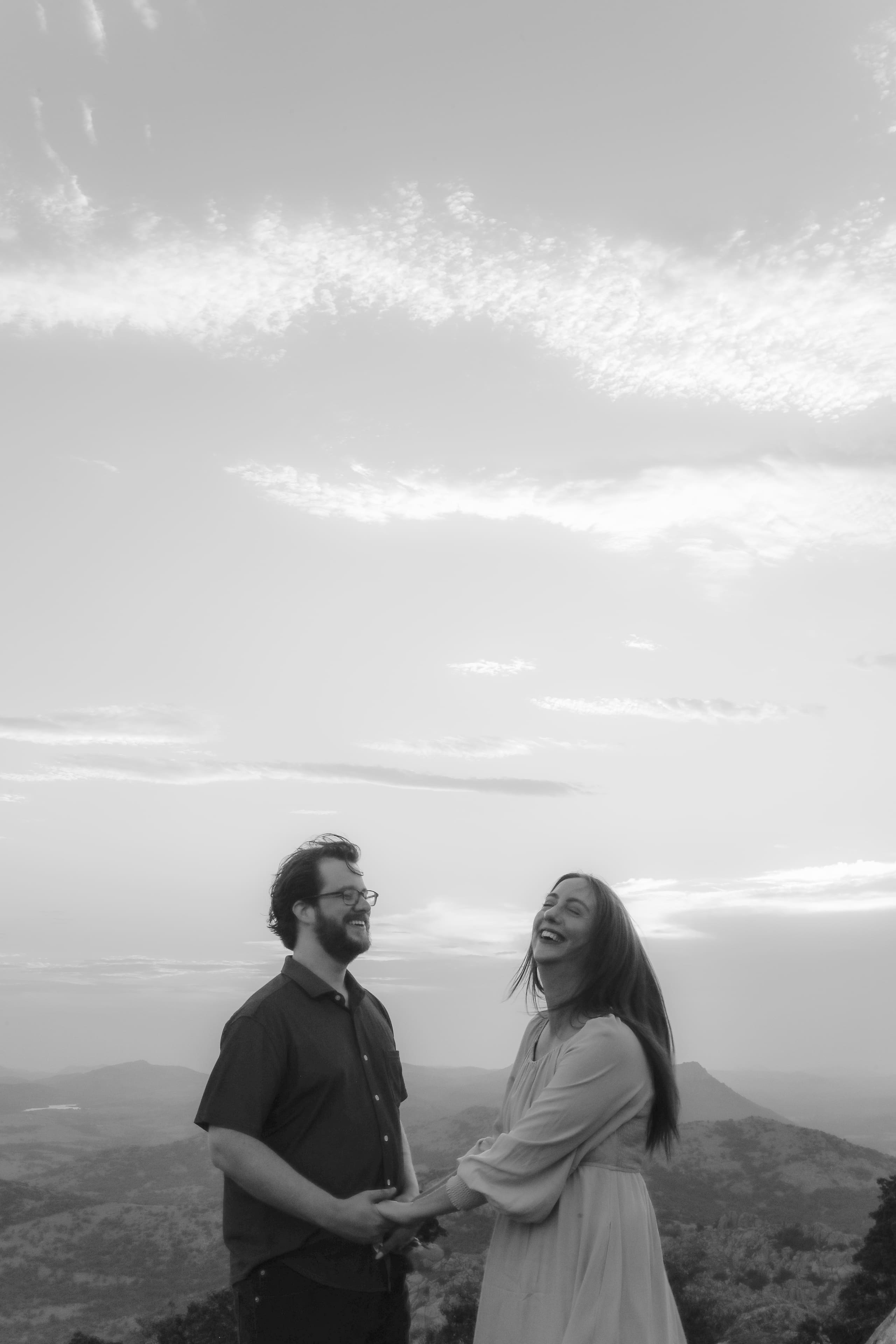 Laughing hand in hand on the summit in black and white