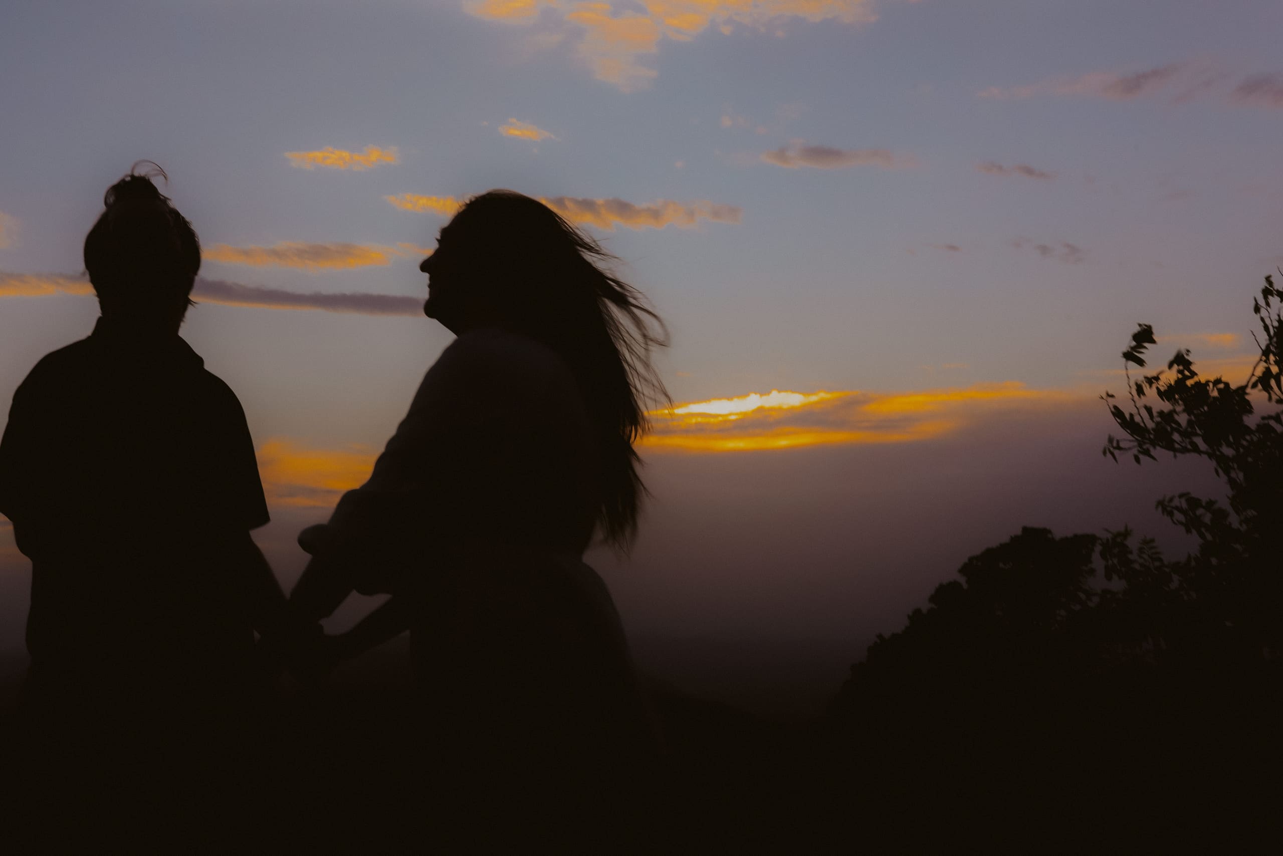 Silhouetted at dusk, her hair lifting in the wind above the glowing horizon