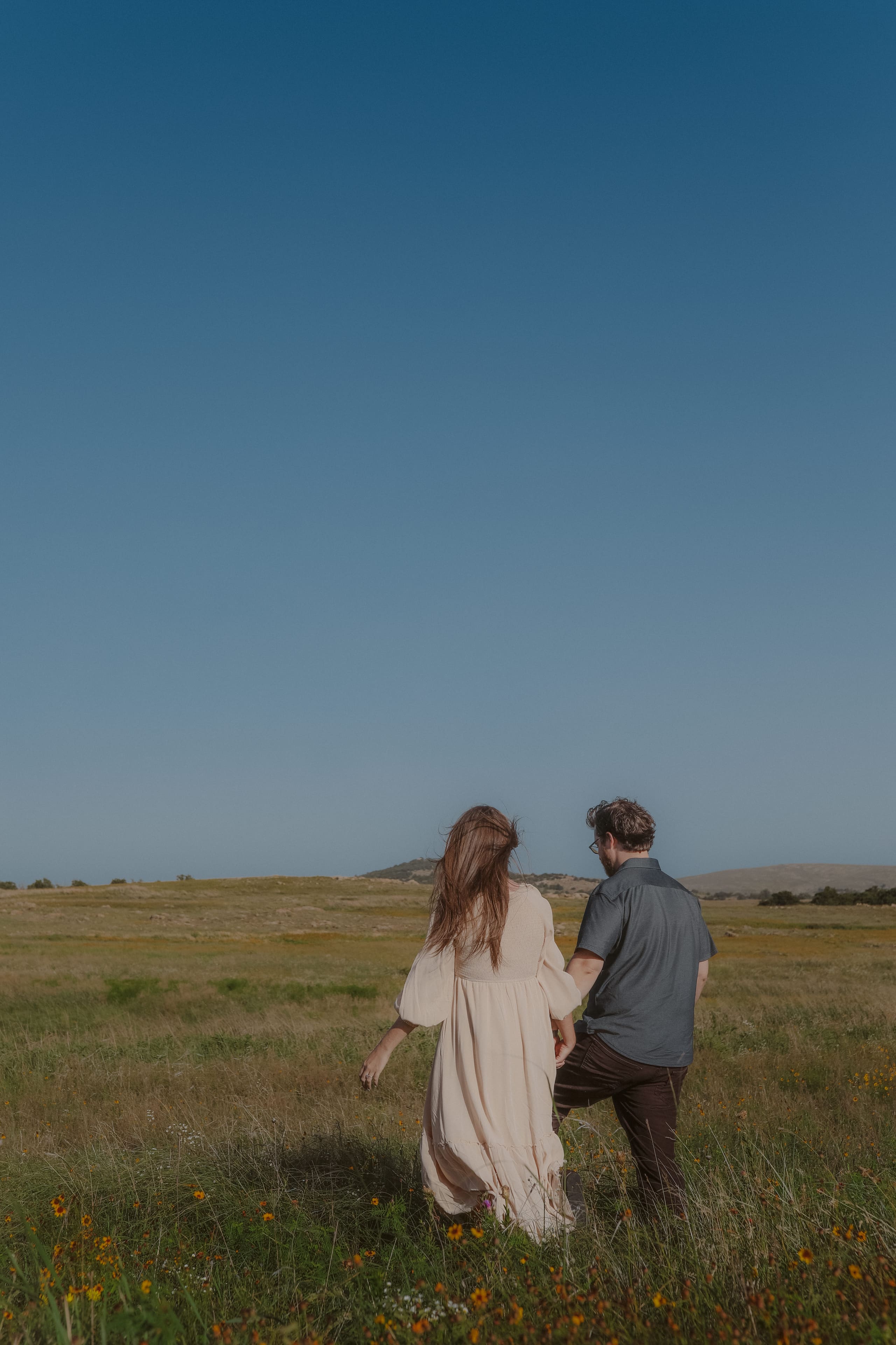 Hand in hand through the wildflower prairie under a wide blue sky
