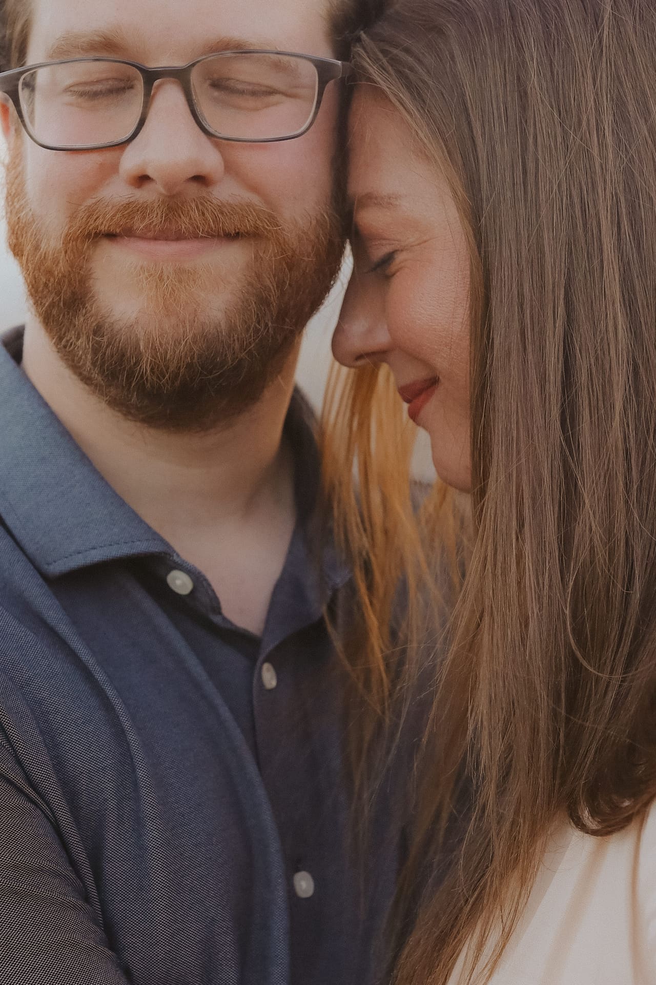 A close portrait — her forehead resting against his cheek, both smiling