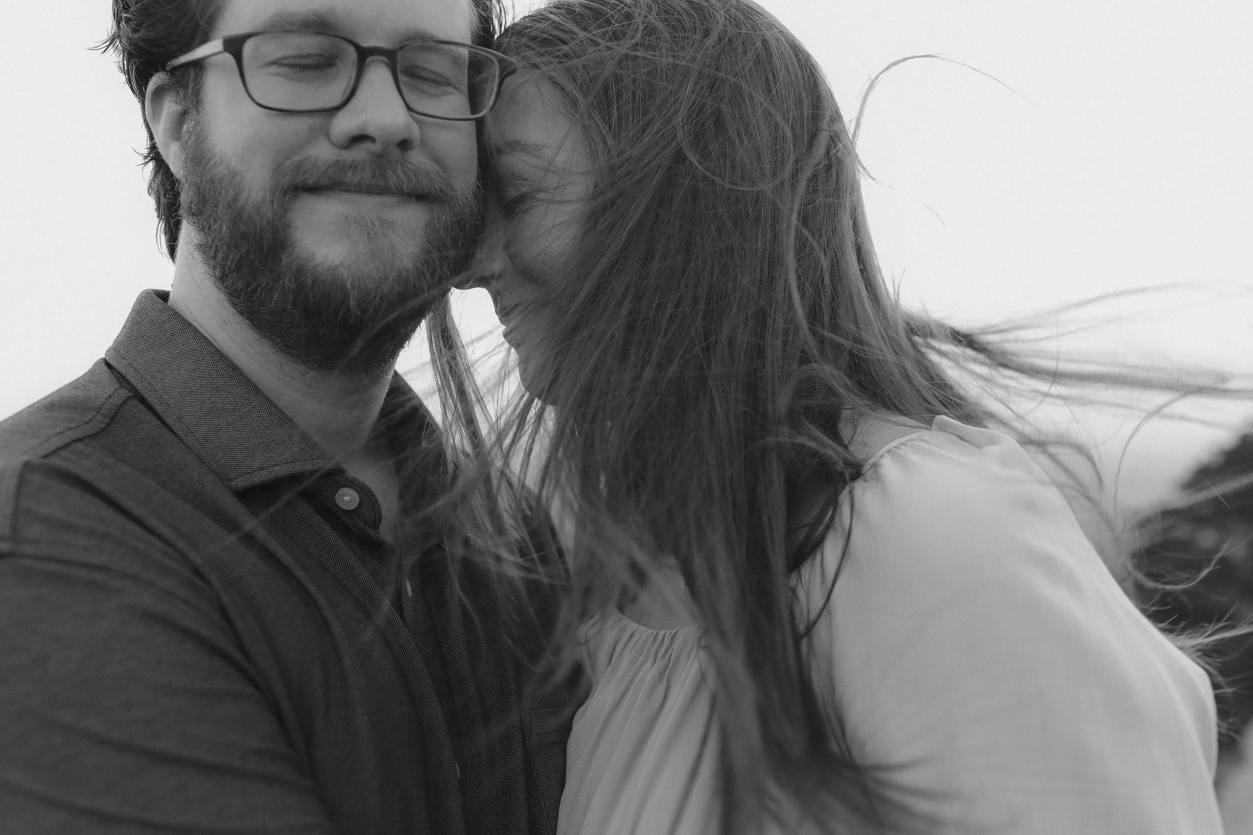 Foreheads touching in black and white, windblown hair across the frame