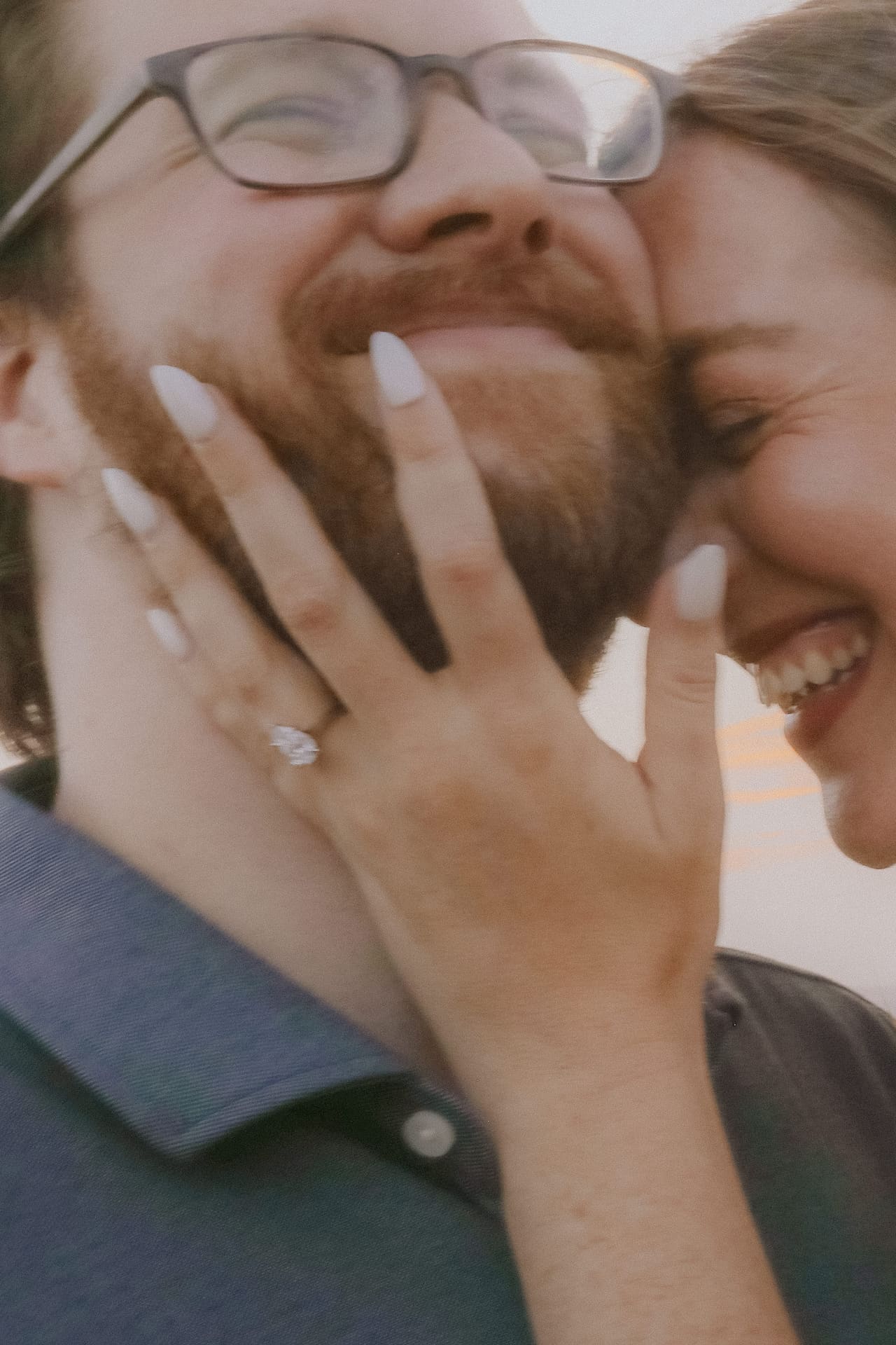 Laughing cheek to cheek, her ring catching the light on his face