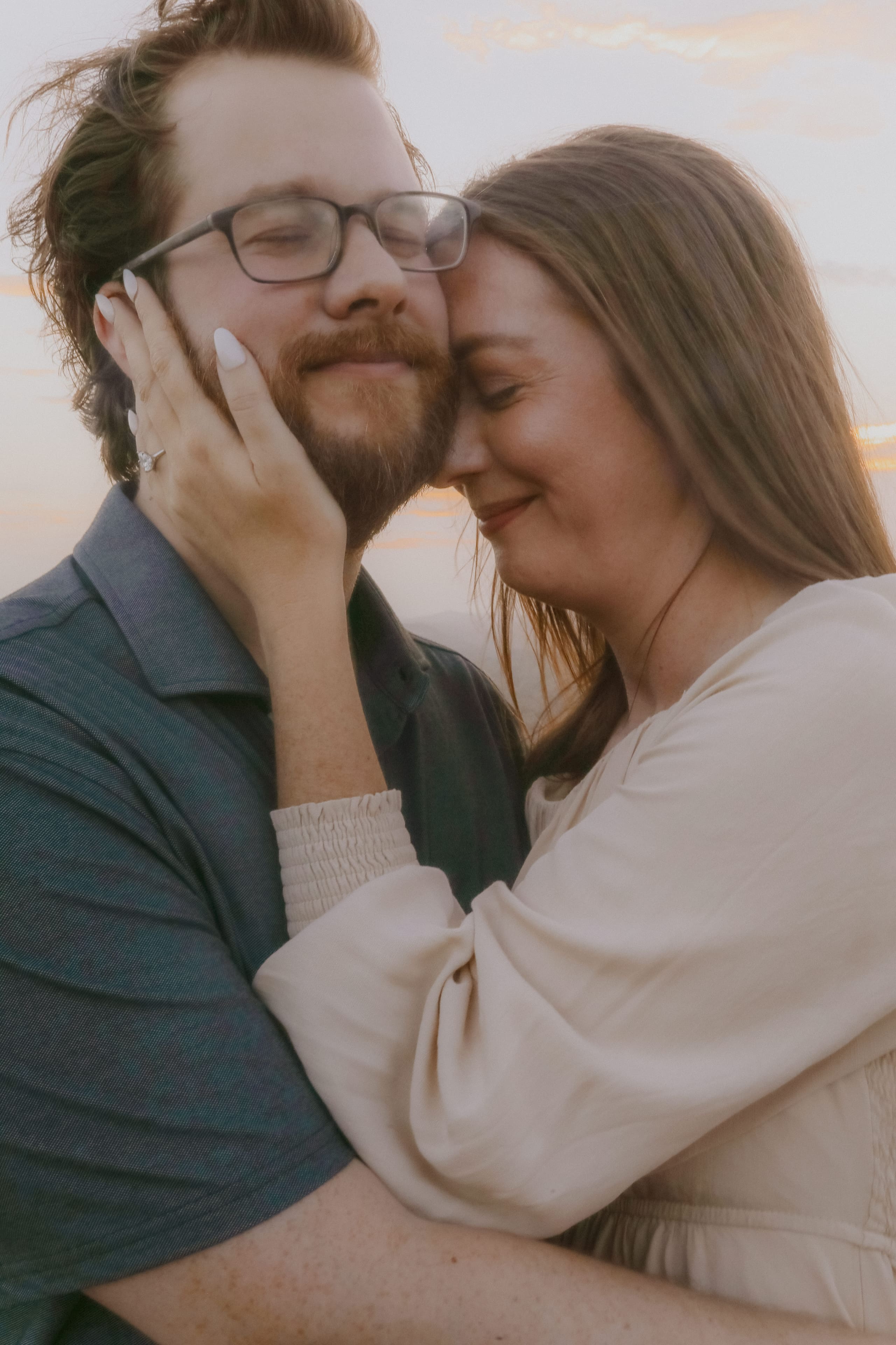 A quiet embrace at sunset, her hand resting on his cheek