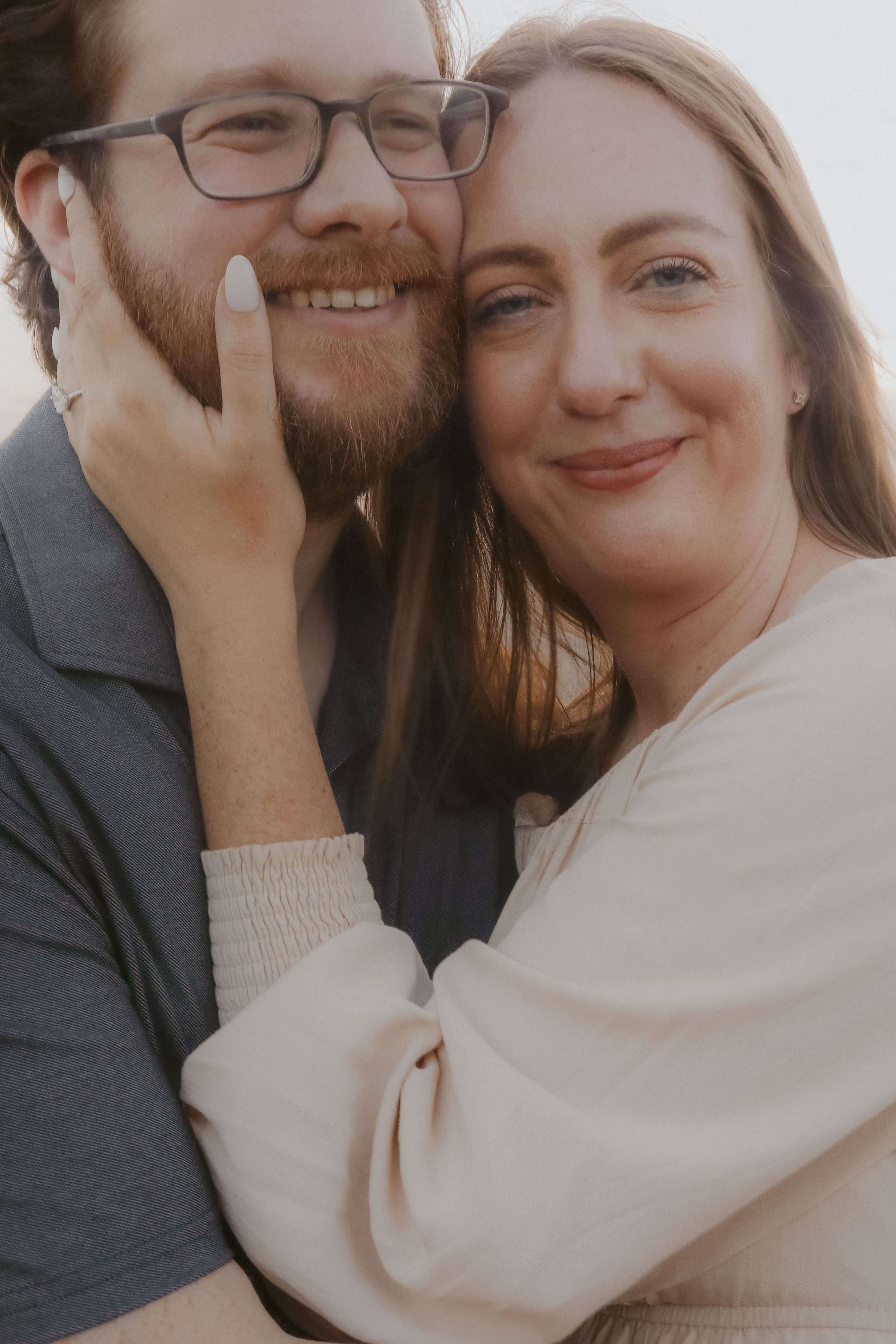 A close portrait — cheek to cheek, both smiling in soft evening light