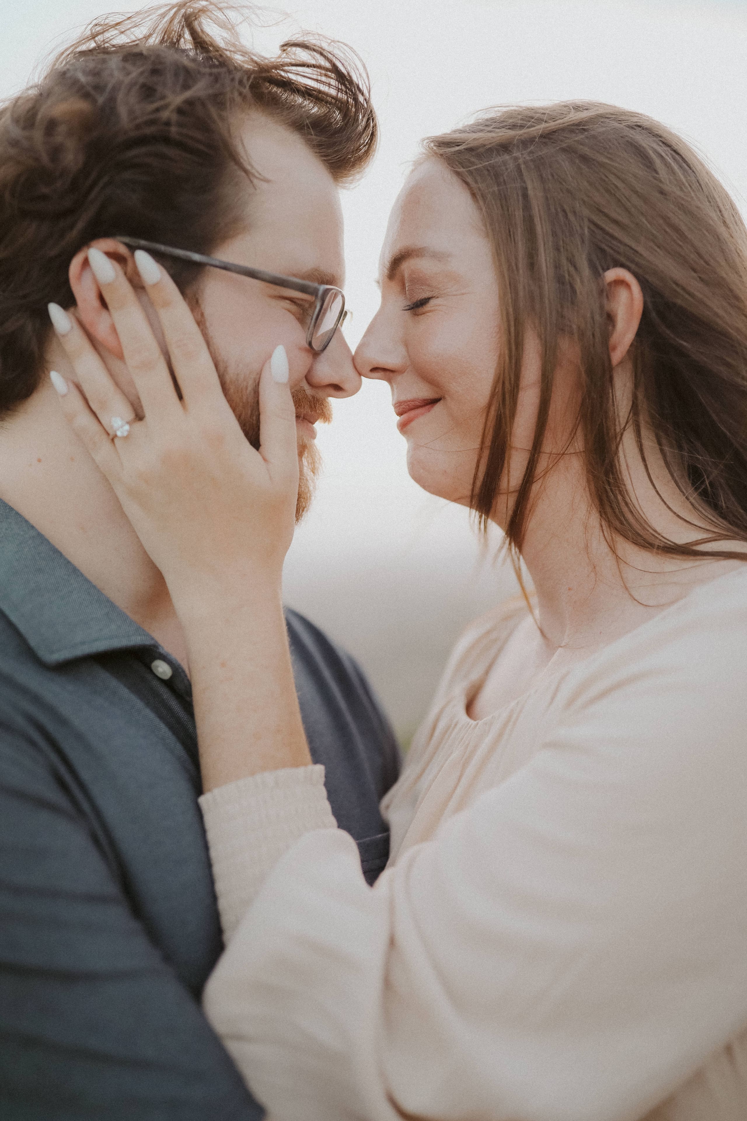 Nose to nose in soft light, her hand resting on his cheek