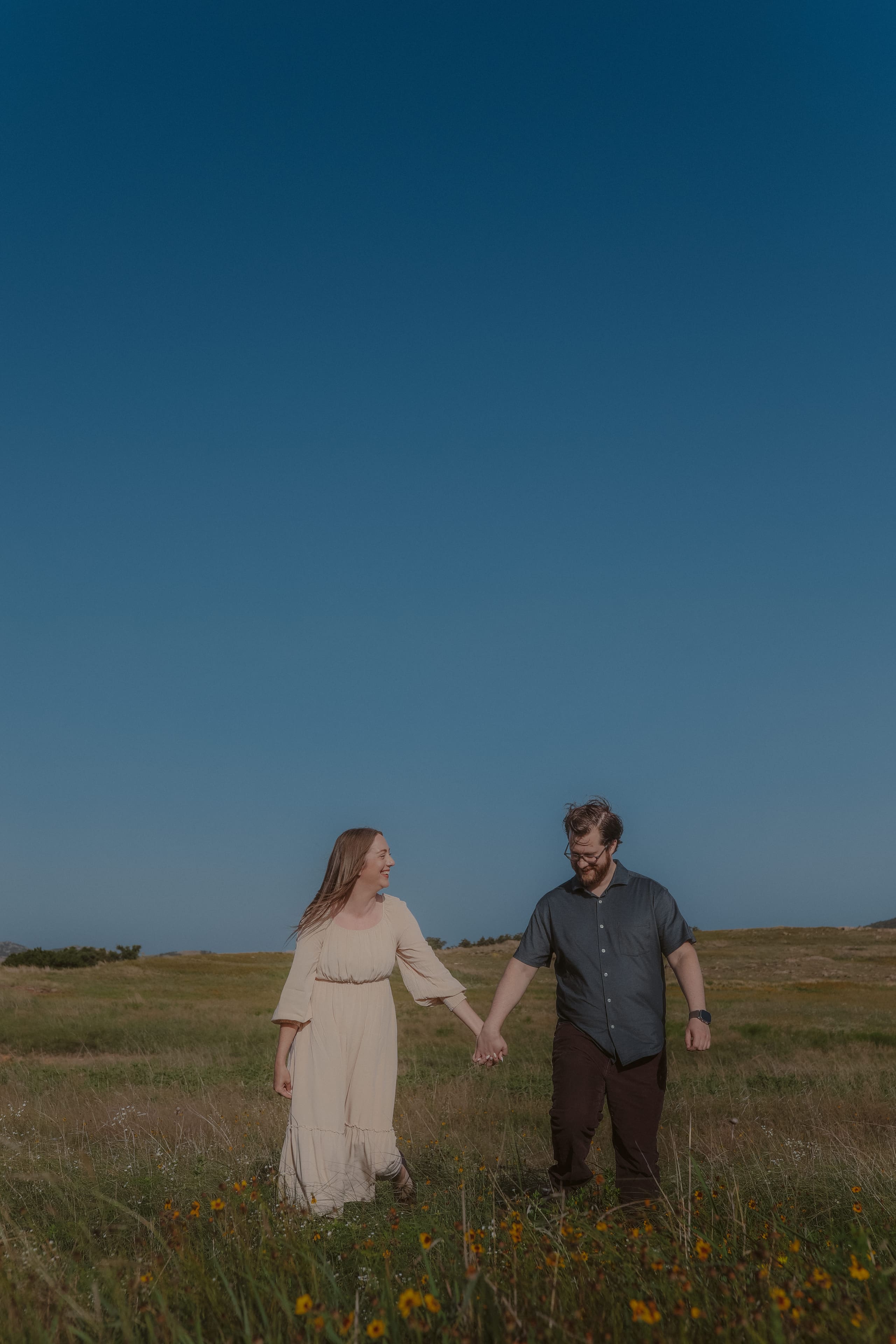 Hand in hand through the wildflower field under a wide blue sky