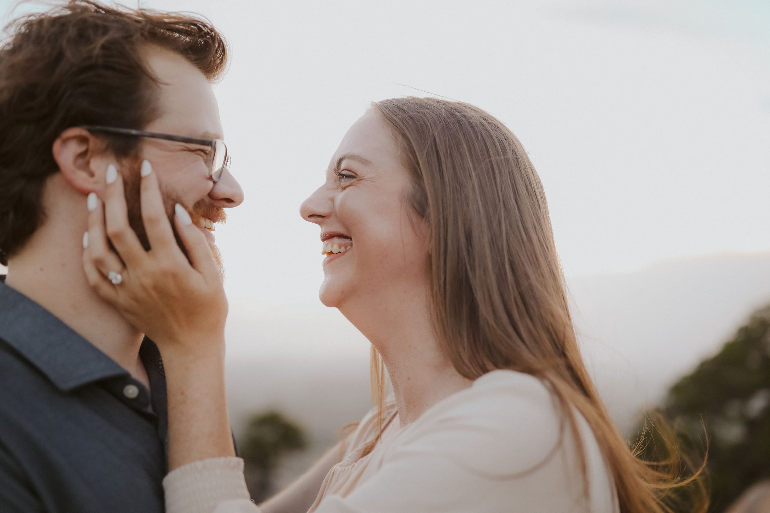 Laughing together, her hands on his face