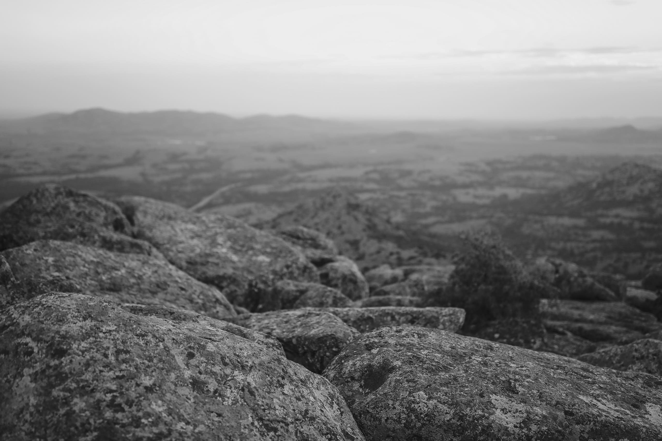 Lichen-covered granite boulders overlooking the hazy plains below