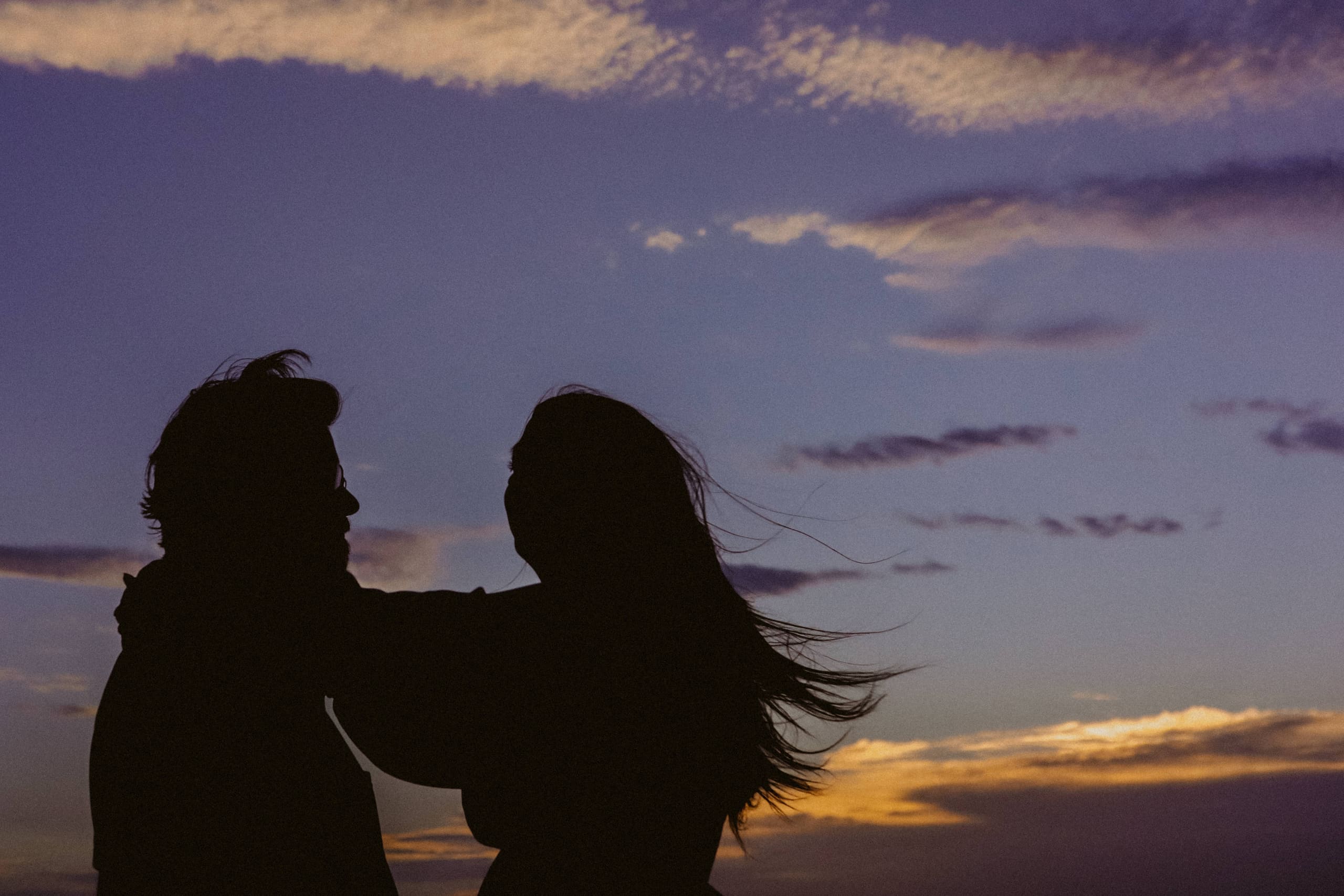 Silhouetted against a violet dusk sky, her hair caught in the wind