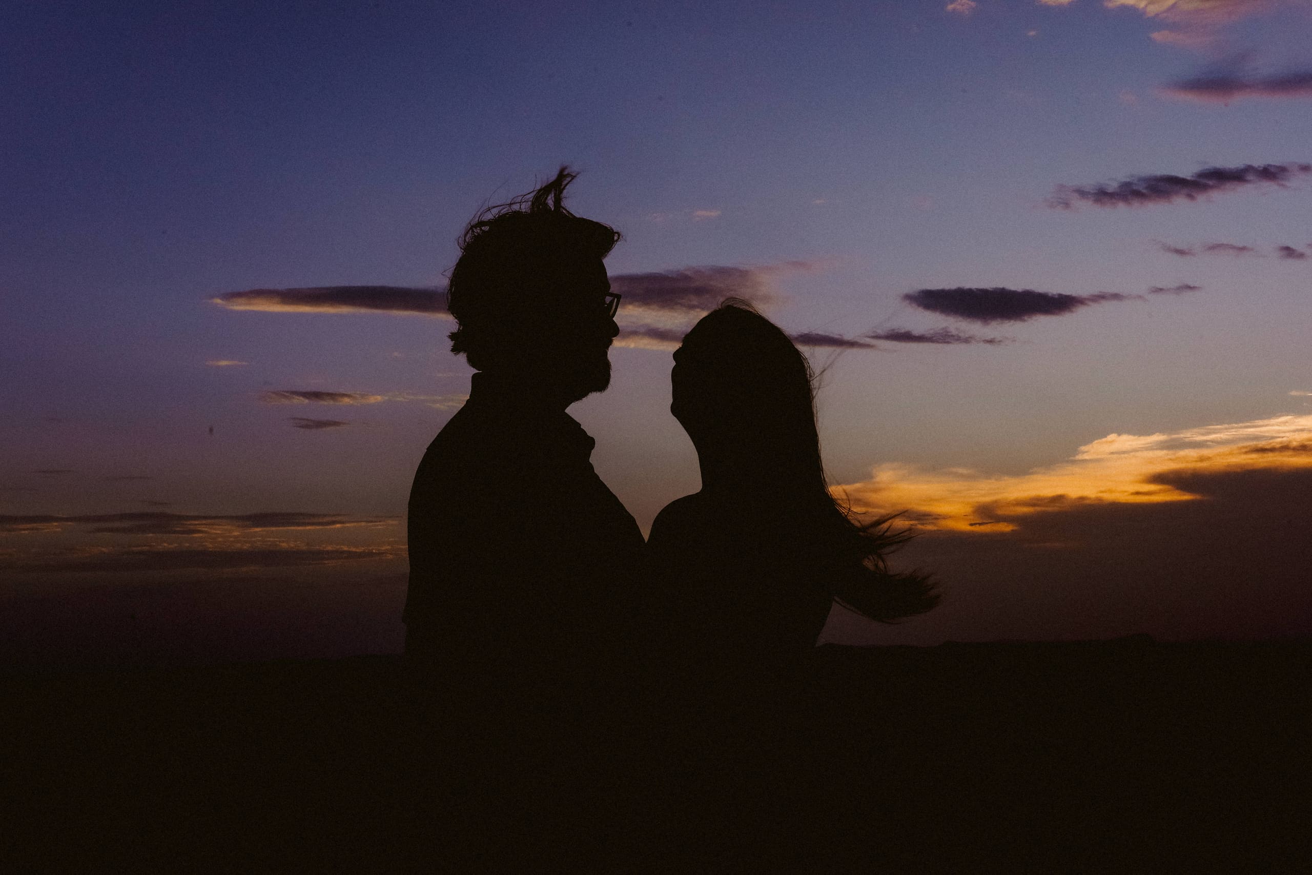 Two silhouettes face to face as the last light fades on the horizon