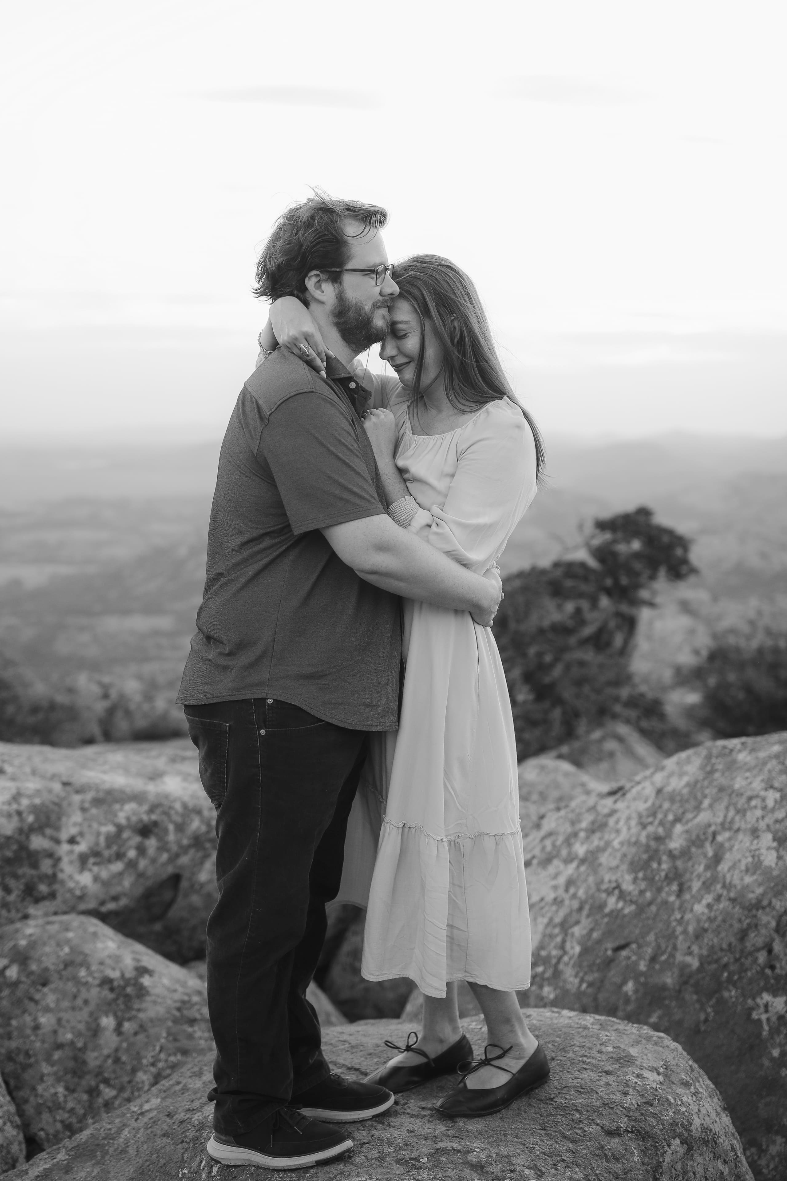 A mountaintop embrace in black and white, forehead pressed to forehead